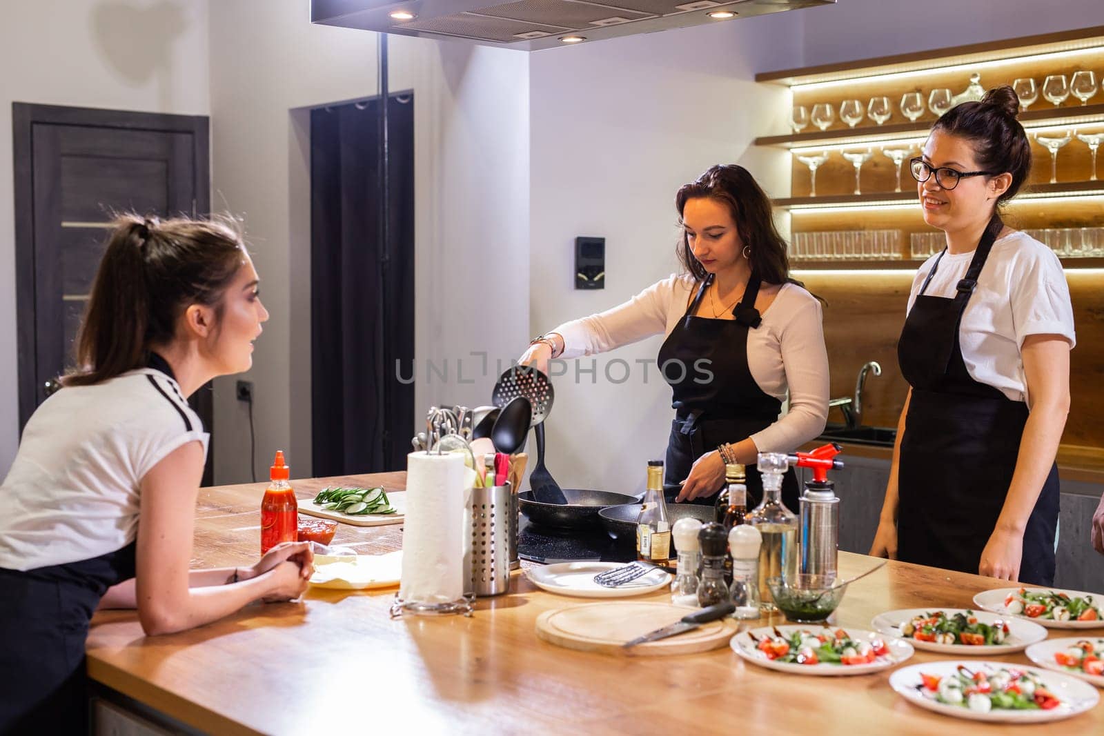 Three funny professional female chefs cooking food in large kitchen and having fun by Satura86