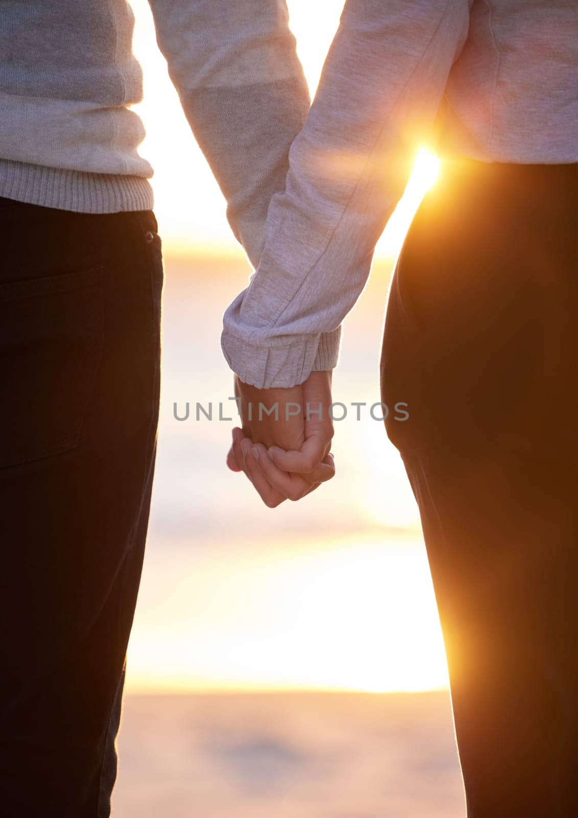 Back of couple holding hands at beach, sunset and vacation of save the date marriage. Closeup hand of man, woman and walking in sunshine, relax and trust of support, peace and love, travel or freedom by YuriArcurs