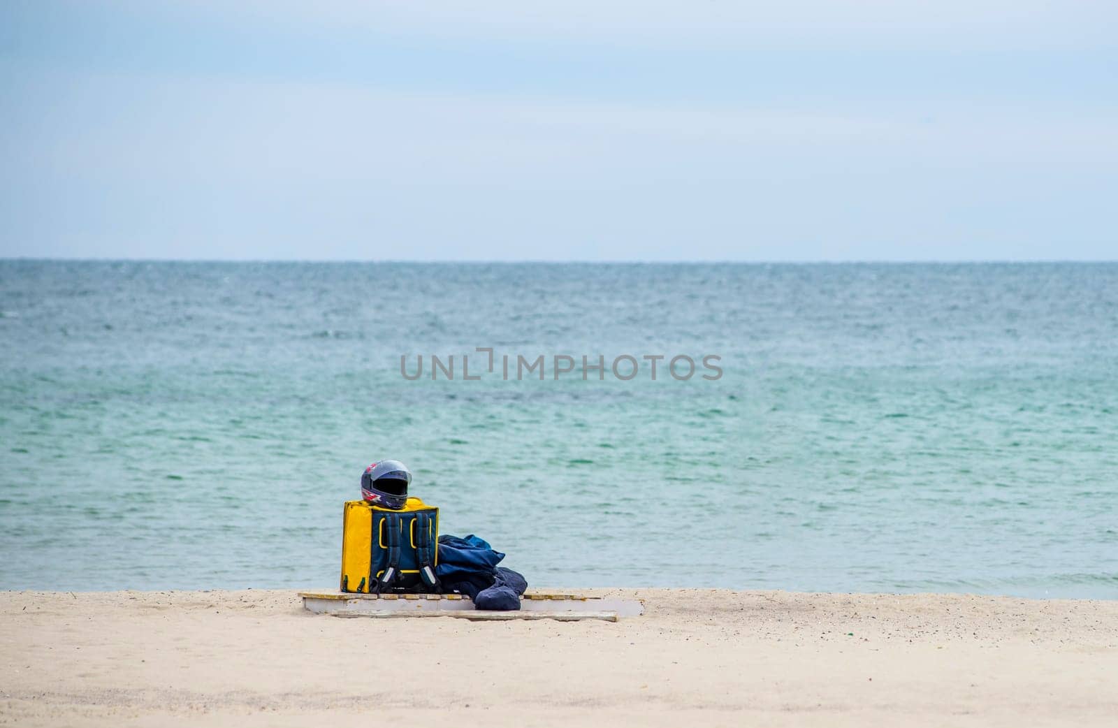 Yellow thermal bag of a food delivery man on the seashore. Fast delivery groceries and food orders from restaurants and cafes. Takeaway food.