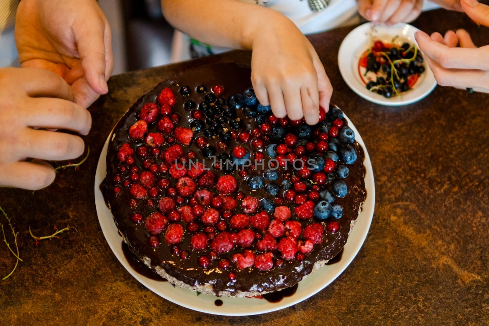 Decorating a chocolate cake with fresh raspberries, blueberries and currants for the whole family. Close up. homemade.