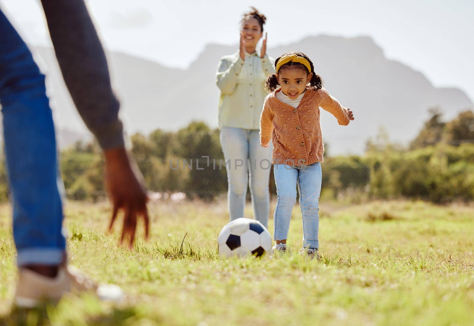 Parents, park and girl kick soccer ball for fun sports learning, bonding and relax in sunshine, garden and nature together. Happy family, little girl and black people playing football on grass field by YuriArcurs