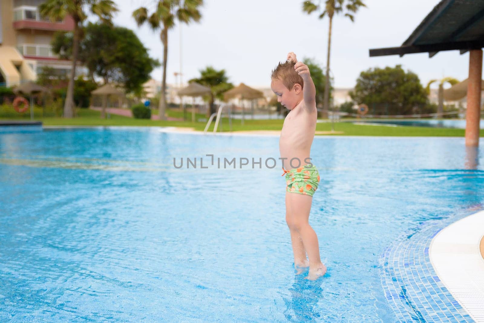 toddler jumping in pool on sunny day.