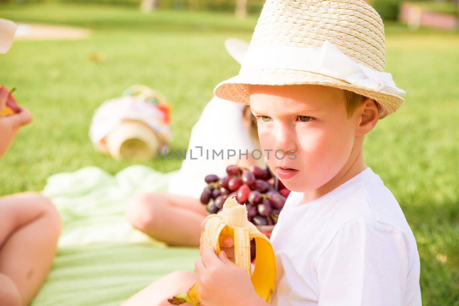 cute little baby boy eats banana by the pool.