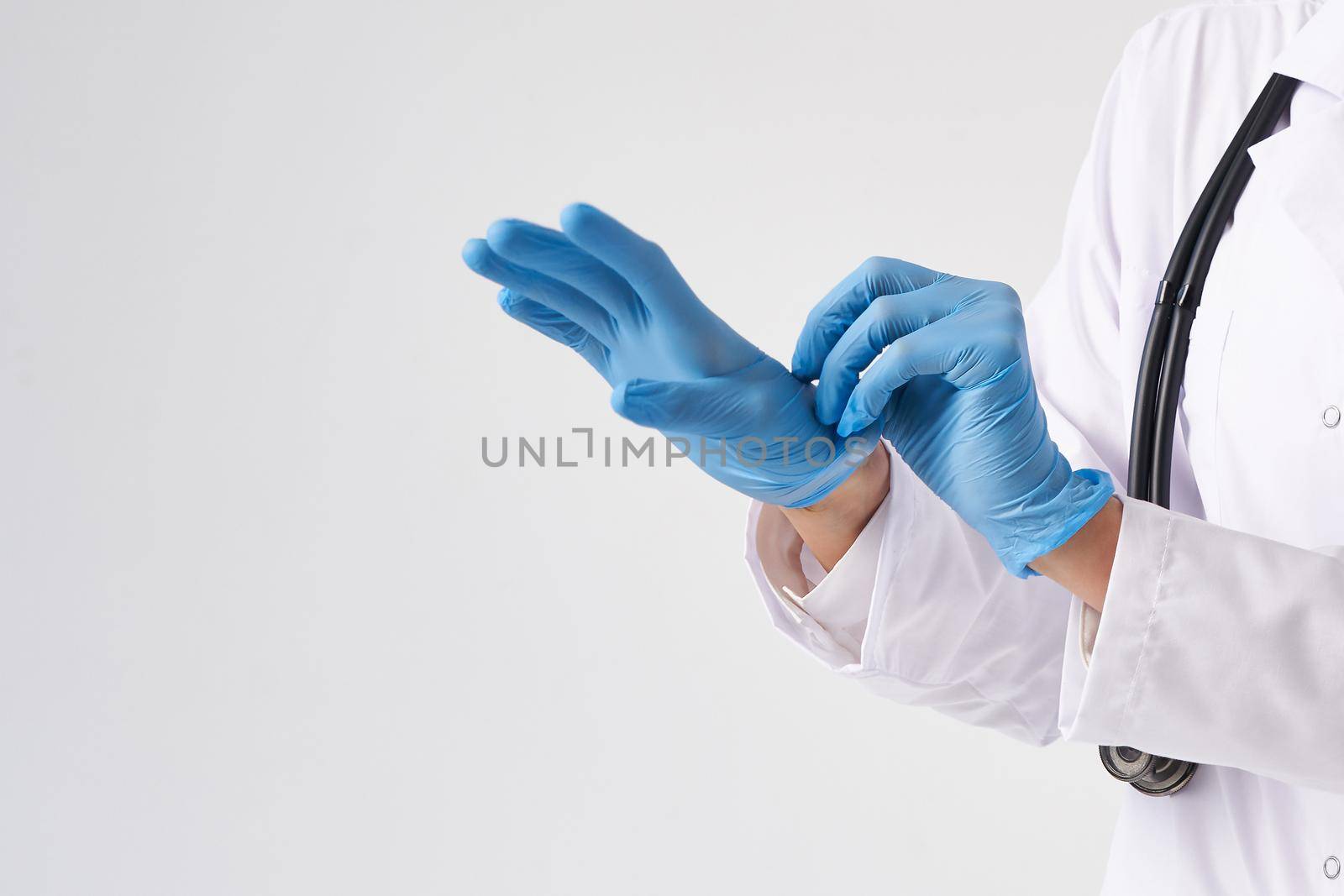 Close up of a female doctor putting latex gloves on a white background