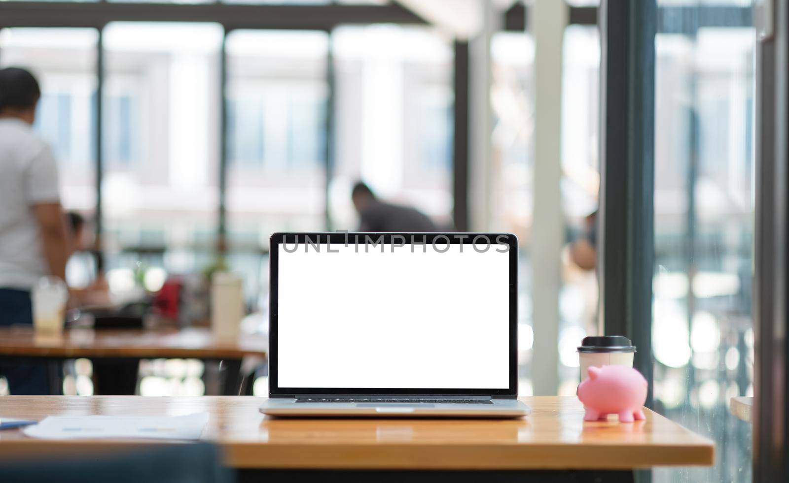 Laptop with blank screen on working desk , financial money saving with pink piggy bank