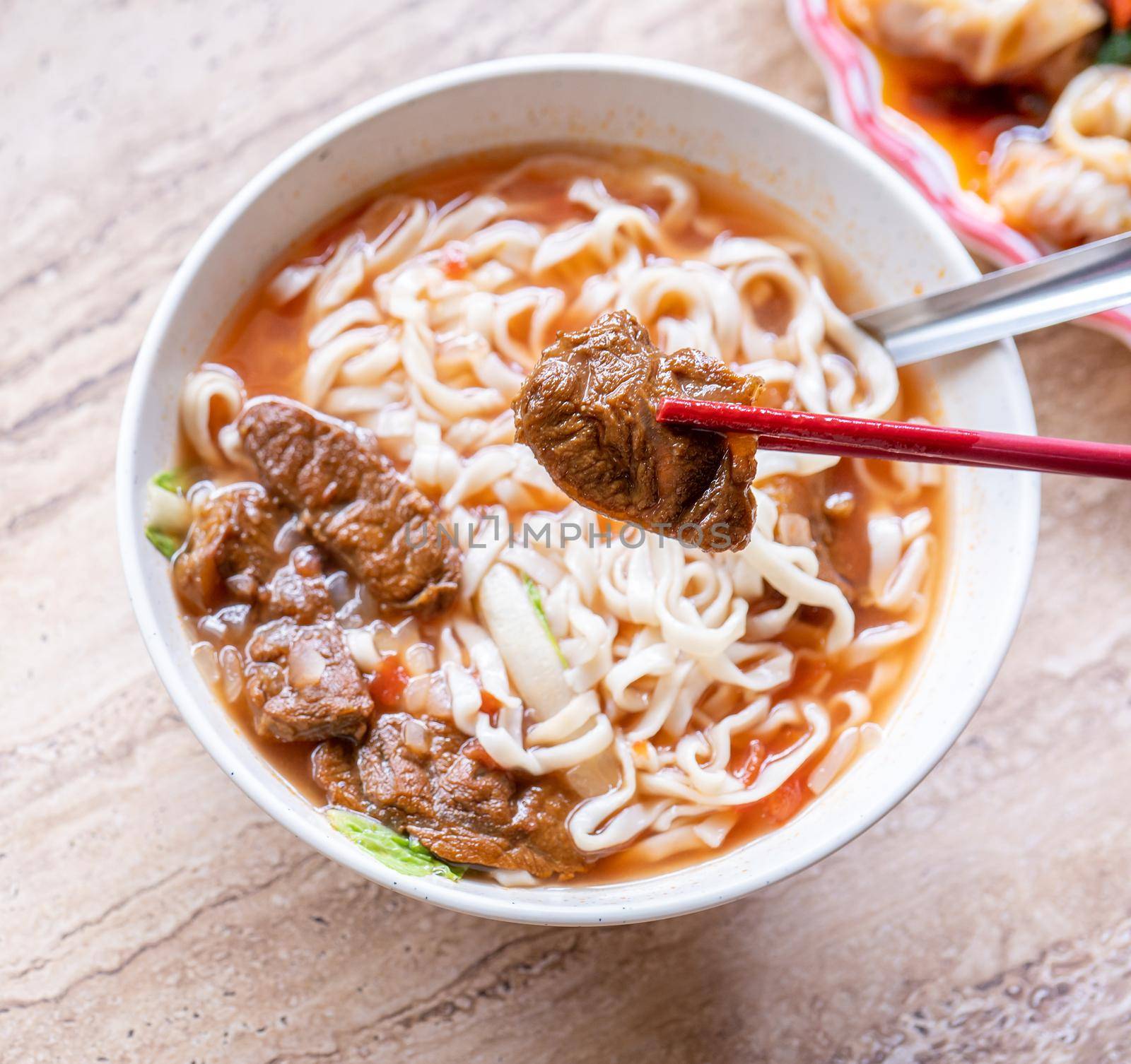 Beef noodle - Taiwan ramen meal with tomato sauce broth in bowl on bright wooden table, famous chinese style food, close up, top view, copy space