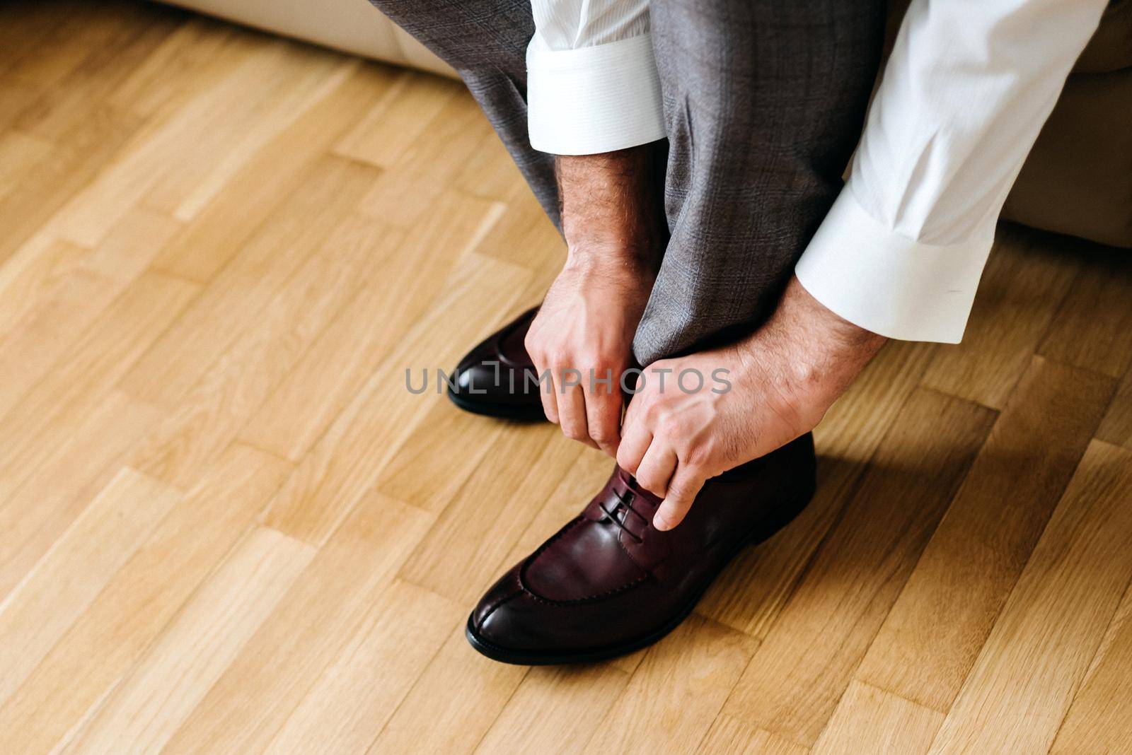 businessman putting on shoes, man getting ready for work, groom morning before wedding ceremony by Mariakray