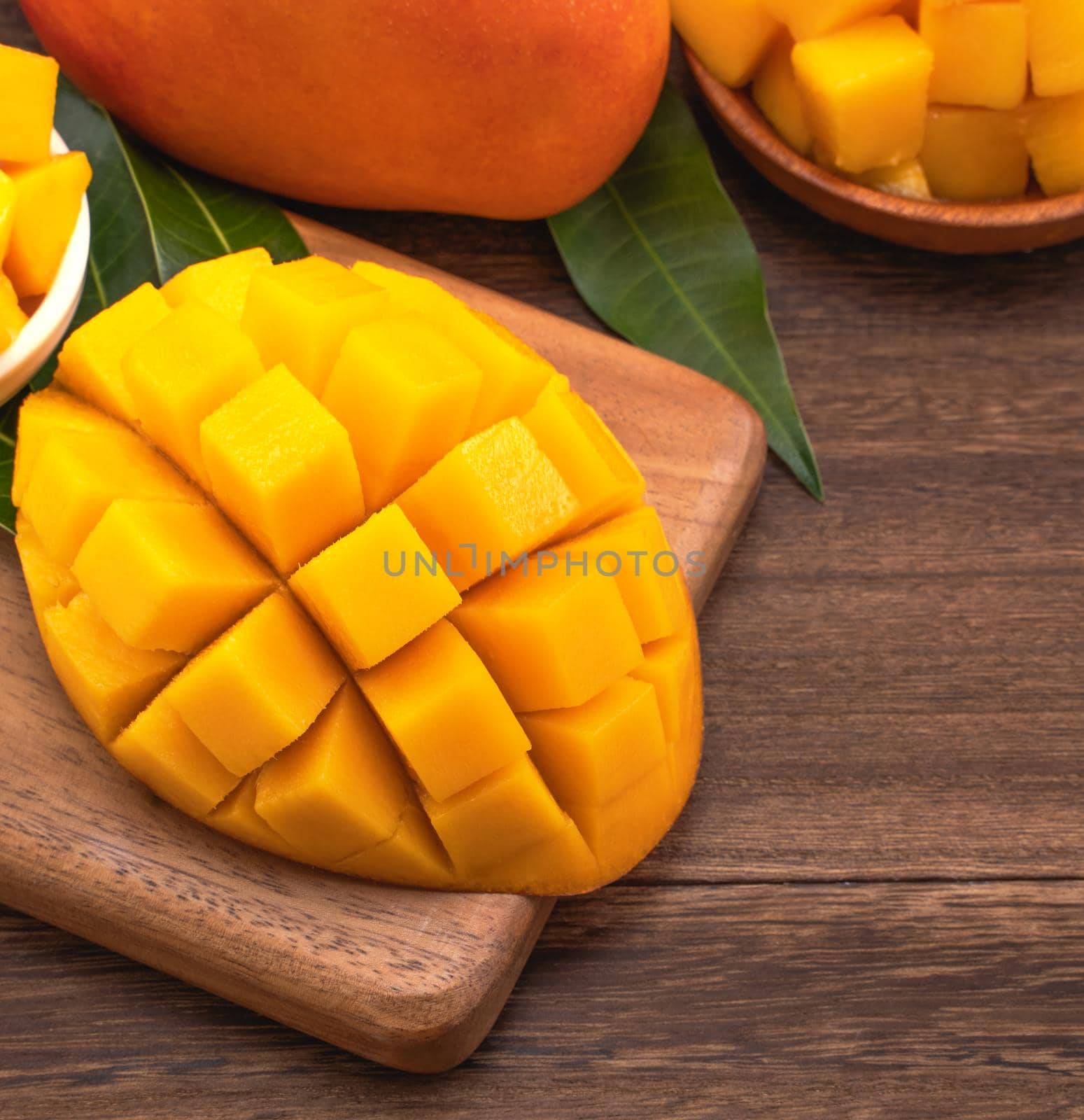 Fresh Mango - Juicy chopped mango cubes on wooden cutting board and rustic timber background. Tropical summer concept. Close up, macro, copy space.  by ROMIXIMAGE
