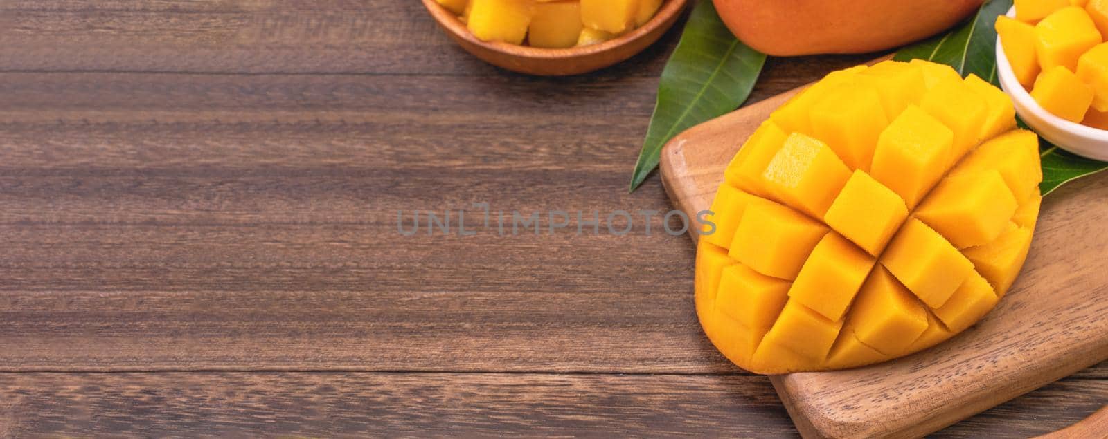 Fresh chopped mango cubes on wooden cutting board and rustic timber background. Tropical summer fruit concept, close up, macro, copy space. by ROMIXIMAGE