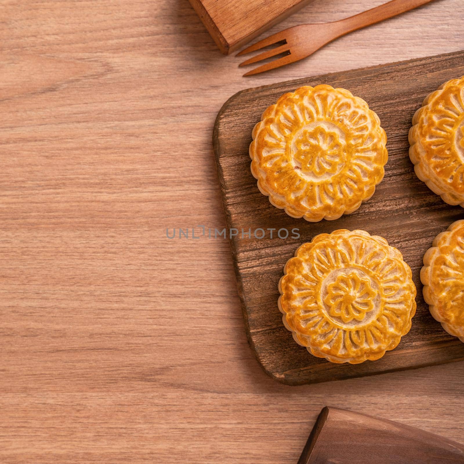 Round shaped moon cake Mooncake - Chinese style pastry during Mid-Autumn Festival / Moon Festival on wooden background and tray, top view, flat lay.