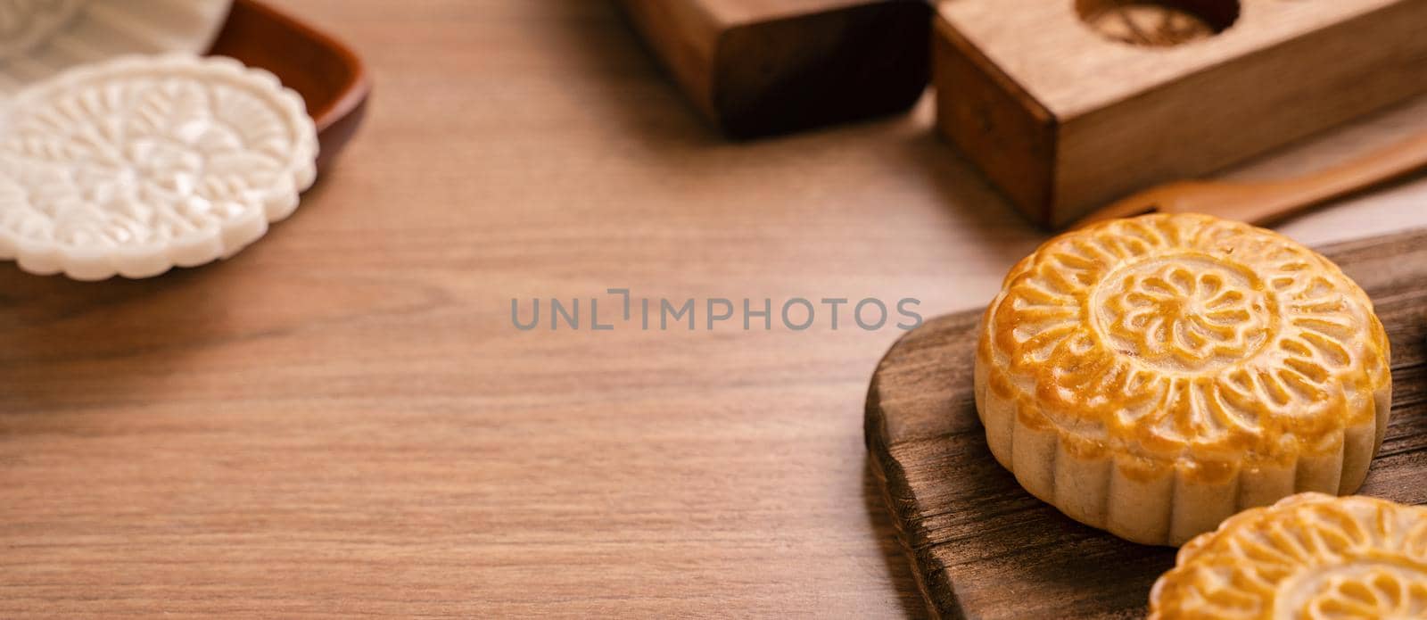 Round shaped moon cake Mooncake - Chinese style traditional pastry during Mid-Autumn Festival / Moon Festival on wooden background and tray, close up by ROMIXIMAGE