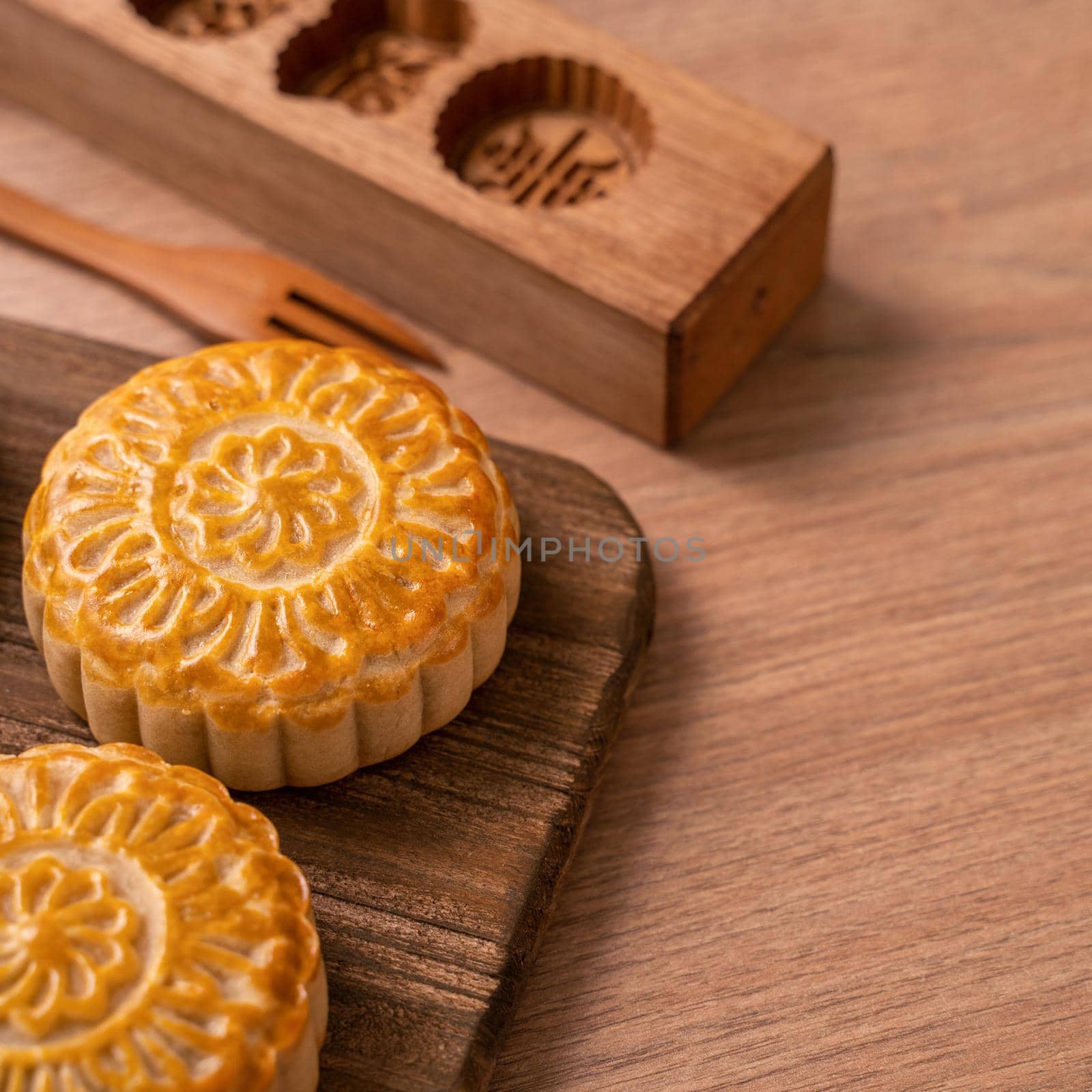 Round shaped moon cake Mooncake - Chinese style traditional pastry during Mid-Autumn Festival / Moon Festival on wooden background and tray, close up