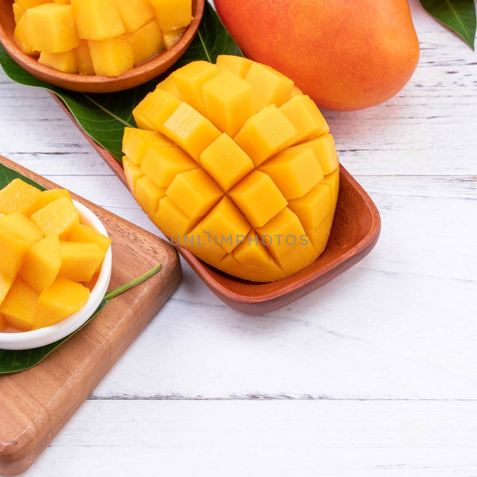 Fresh chopped mango on a tray and bright rustic wooden background. Tropical summer fruit design concept, close up, macro, copy space.