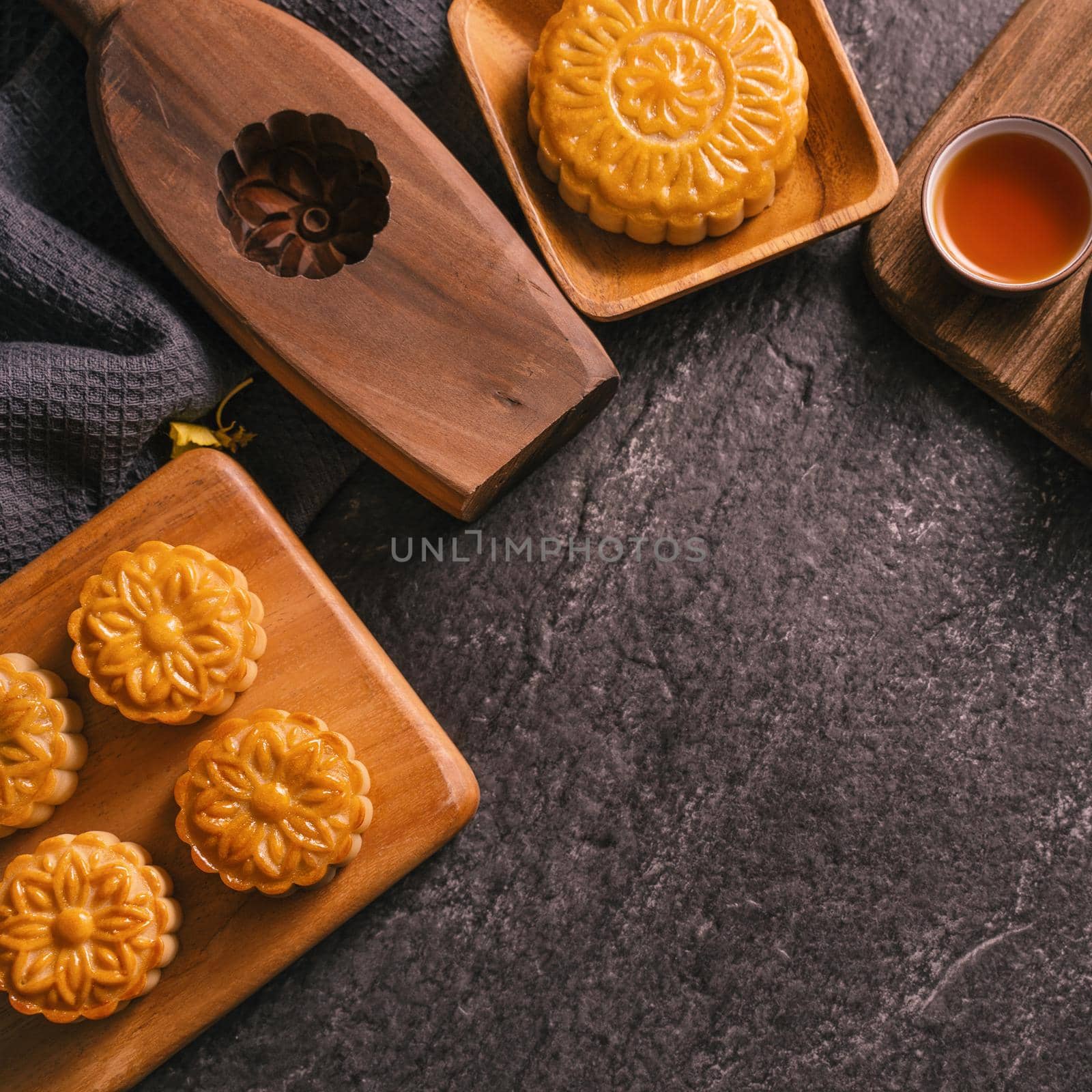 Mid-Autumn Festival traditional food concept - Beautiful Moon cake on black slate table with tea, pastry mold, flower, top view, flat lay, copy space