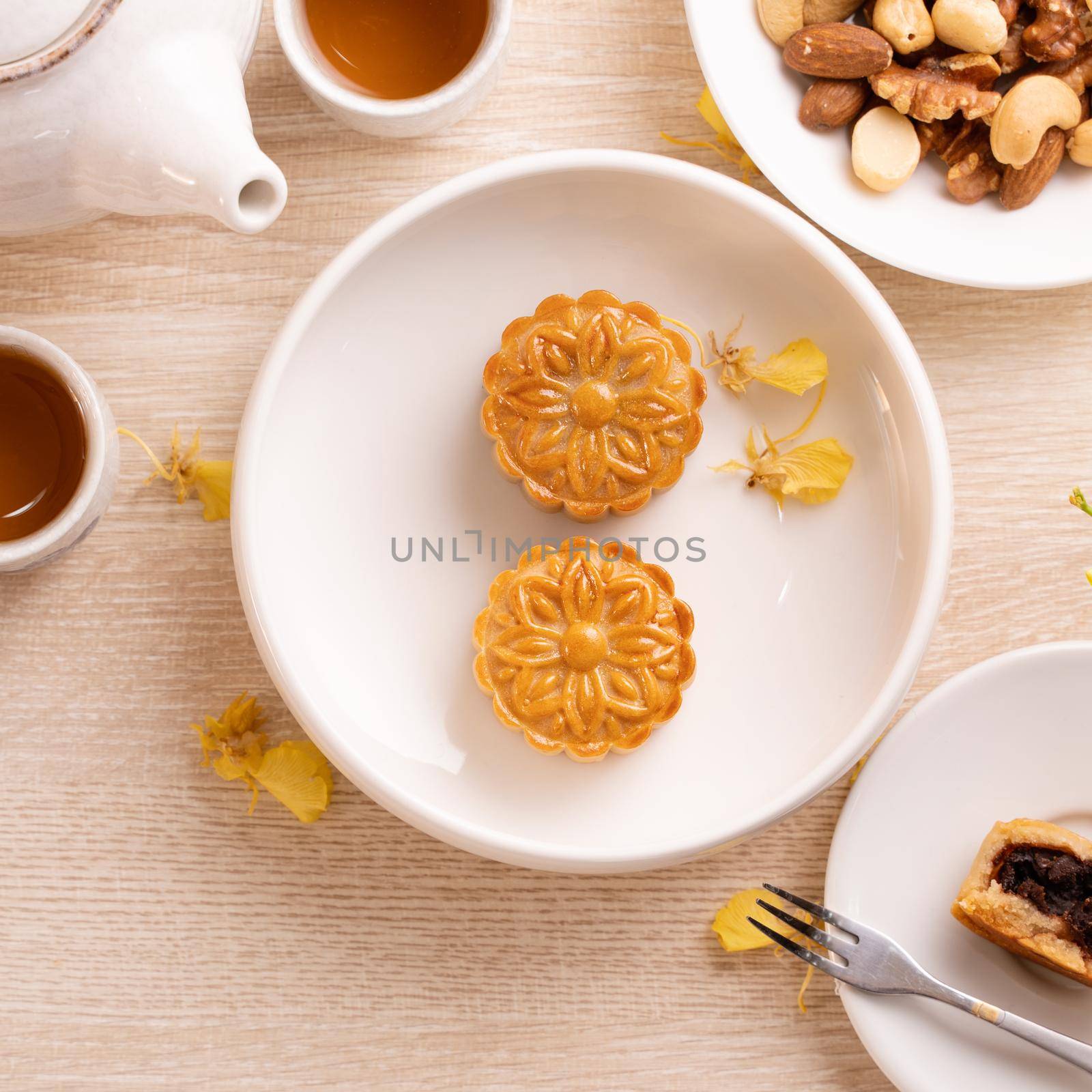 Delicious moon cake for Mid-Autumn festival with beautiful pattern, decorated with yellow flowers and tea. Concept of festive afternoon pastry design