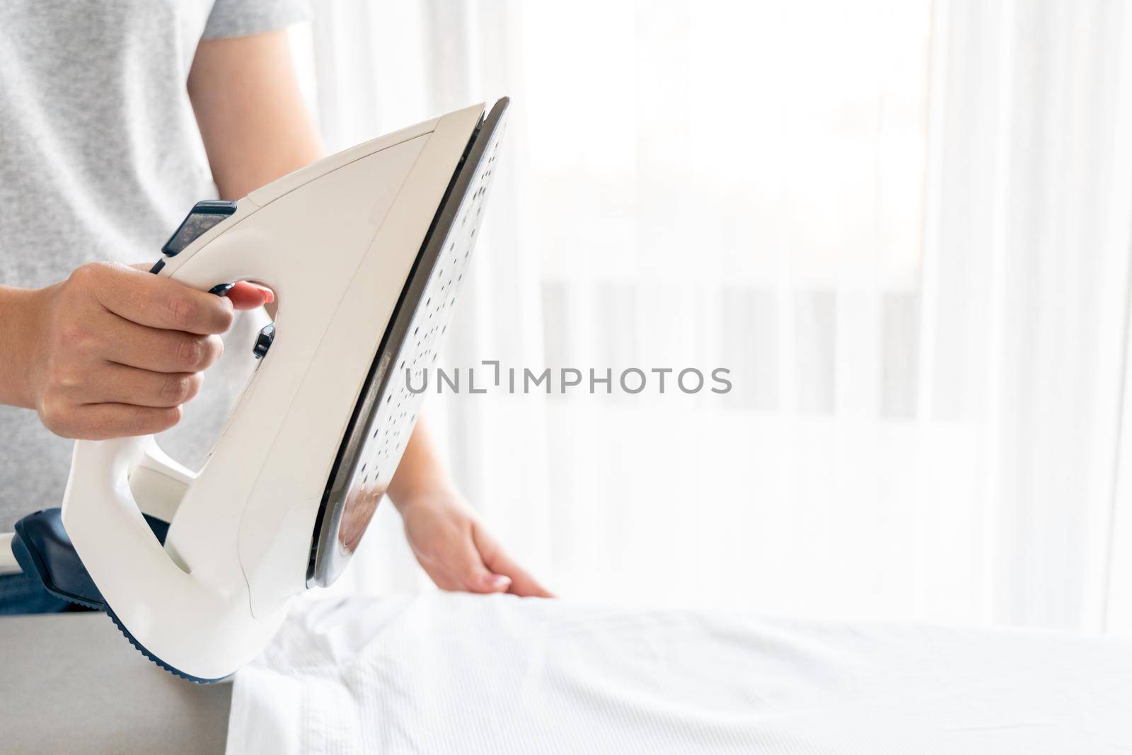 Close up of Female hands ironing white shirt on ironing board