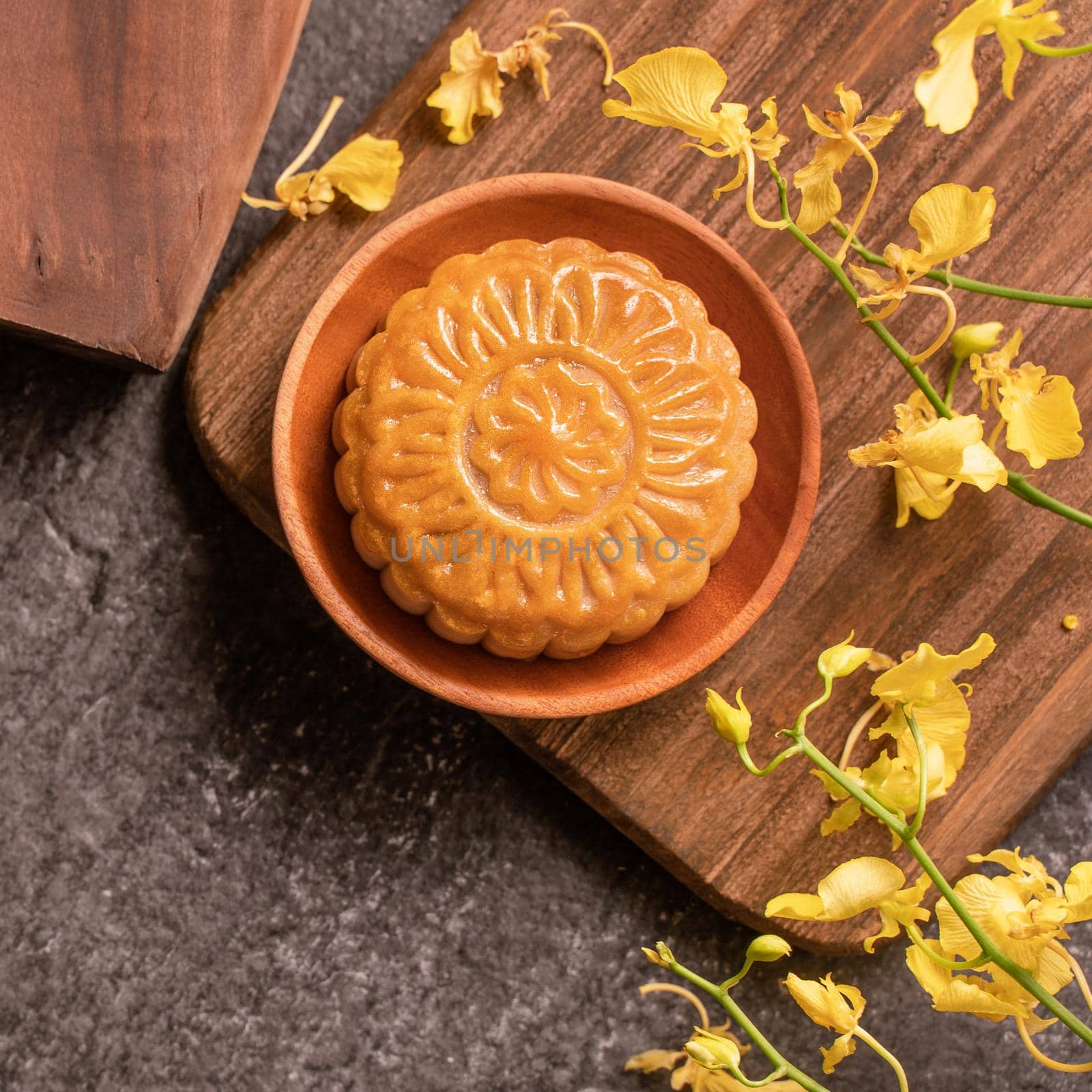 Mid-Autumn Festival traditional food concept - Beautiful Moon cake on black slate table with tea, pastry mold, flower, top view, flat lay, copy space