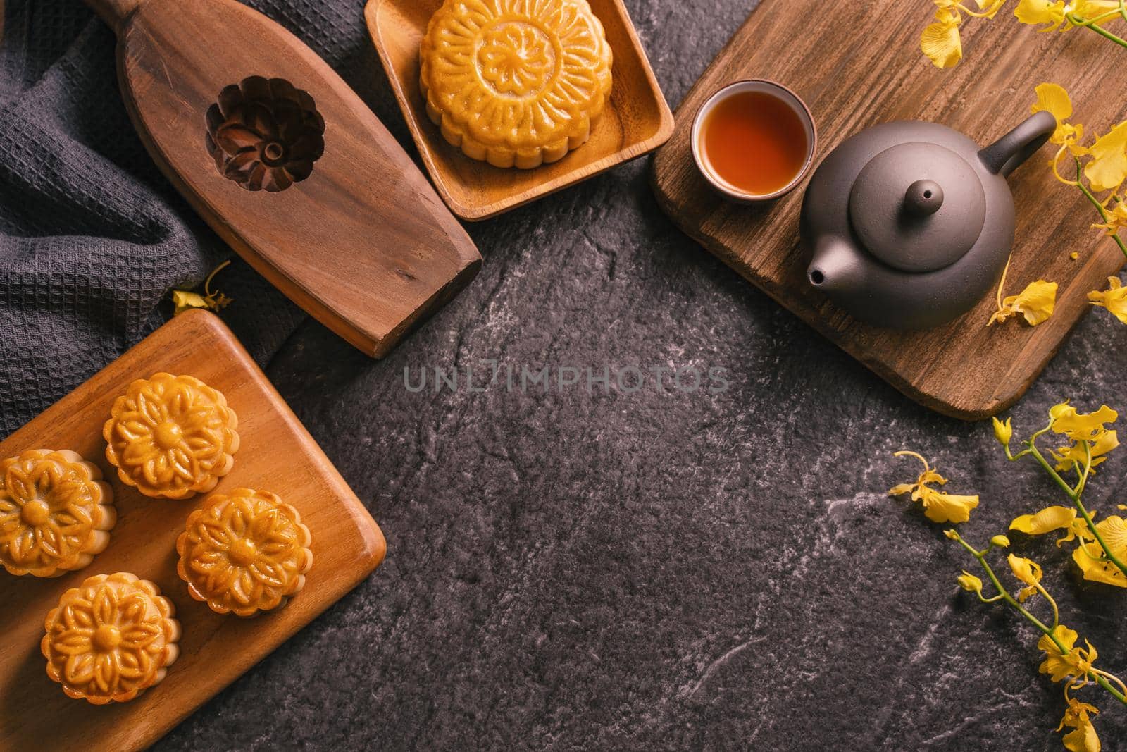 Mid-Autumn Festival traditional food concept - Beautiful Moon cake on black slate table with tea, pastry mold, flower, top view, flat lay, copy space
