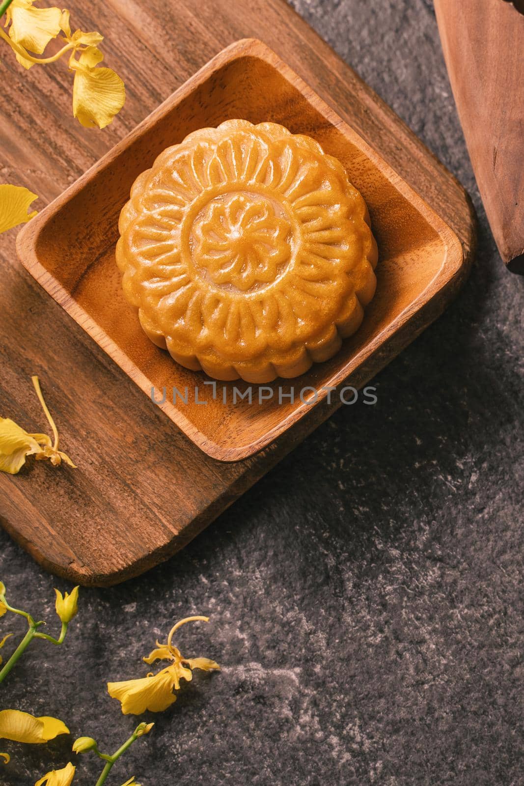 Mid-Autumn Festival traditional food concept - Beautiful Moon cake on black slate table with tea, pastry mold, flower, top view, flat lay, copy space