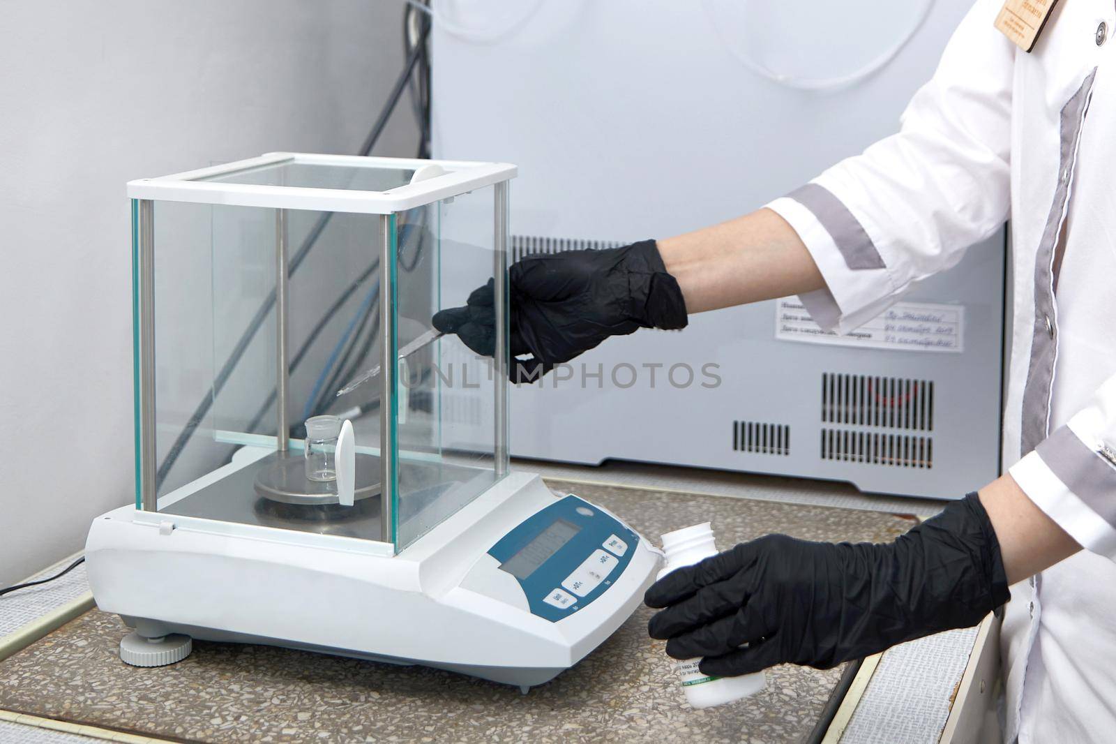 Scientist weighing chemicals by digital scales in grams in chemical laboratory by Mariakray