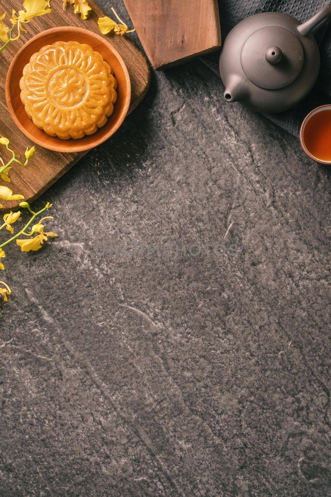 Mid-Autumn Festival traditional food concept - Beautiful Moon cake on black slate table with tea, pastry mold, flower, top view, flat lay, copy space