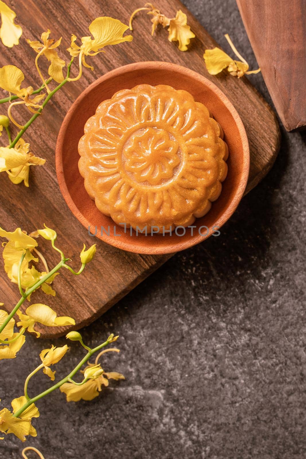 Mid-Autumn Festival traditional food concept - Beautiful Moon cake on black slate table with tea, pastry mold, flower, top view, flat lay, copy space