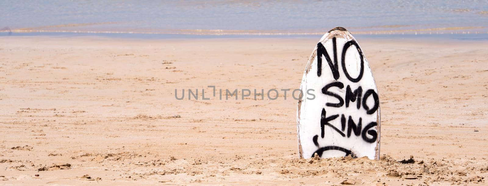 No Smoking warning sign on white surfboard at the beach in summer, concept of sea environmantal protection design, copy space, lifestyle.