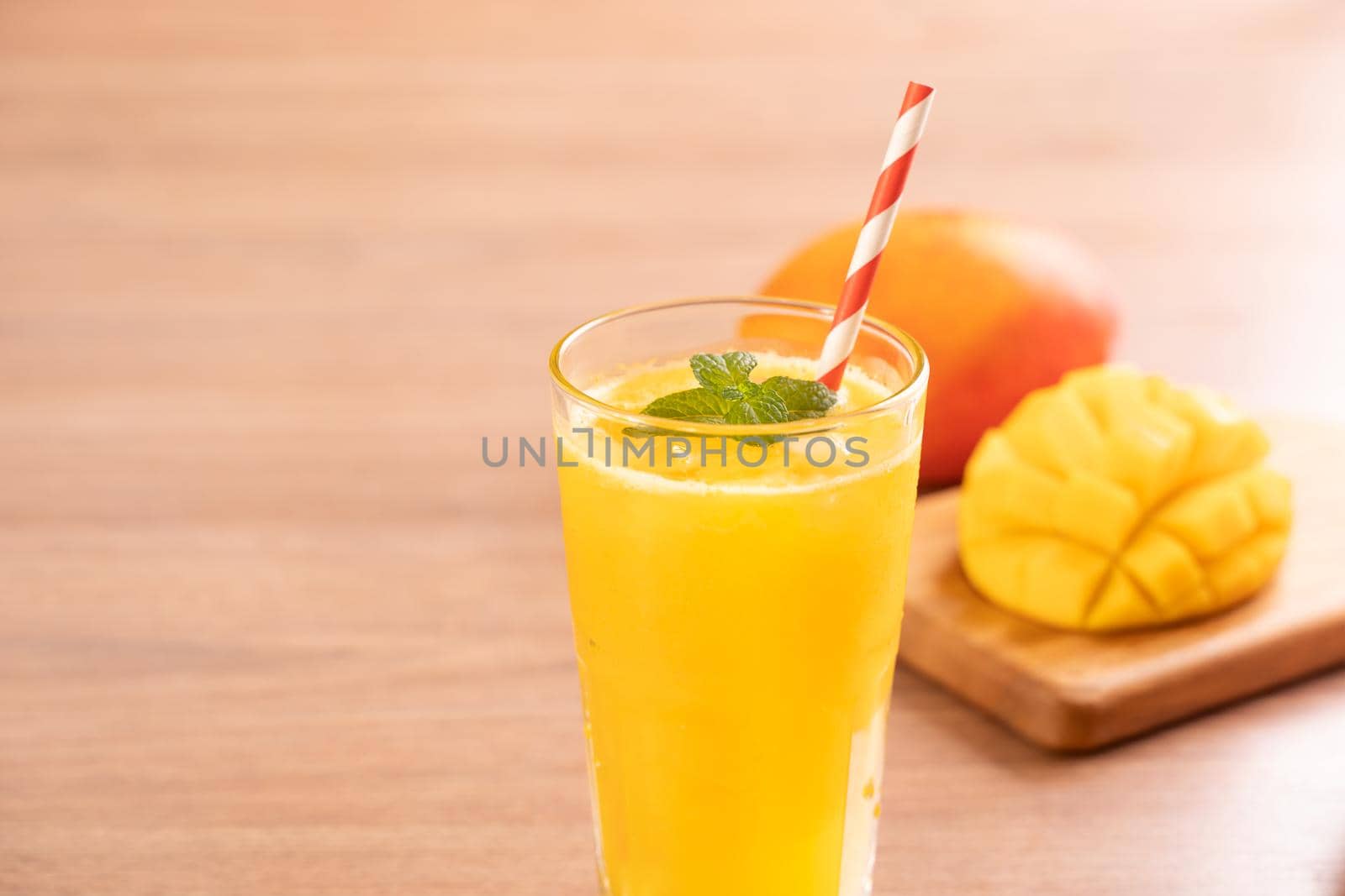 Fresh mango juice with beautiful chopped pulp flesh on bright wooden table background. Tropical fruit drink design concept. Close up, copy space.