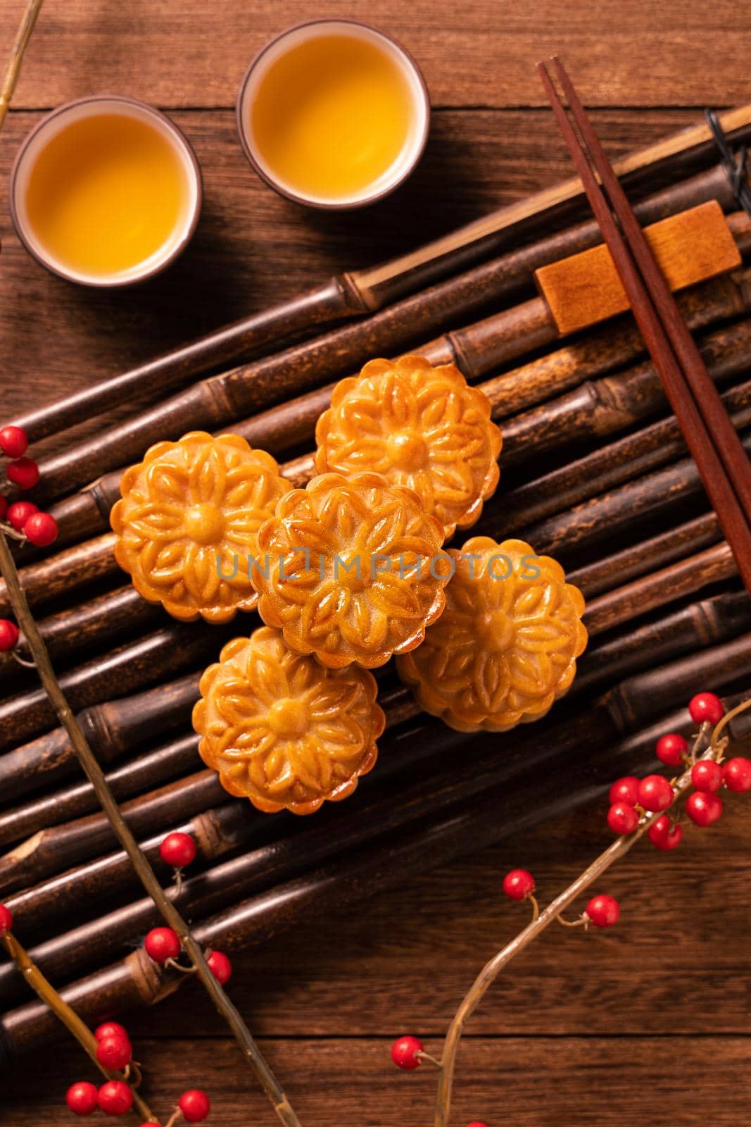 Chinese traditional pastry Moon cake Mooncake with tea cups on bamboo serving tray on wooden background for Mid-Autumn Festival, top view, flat lay. by ROMIXIMAGE