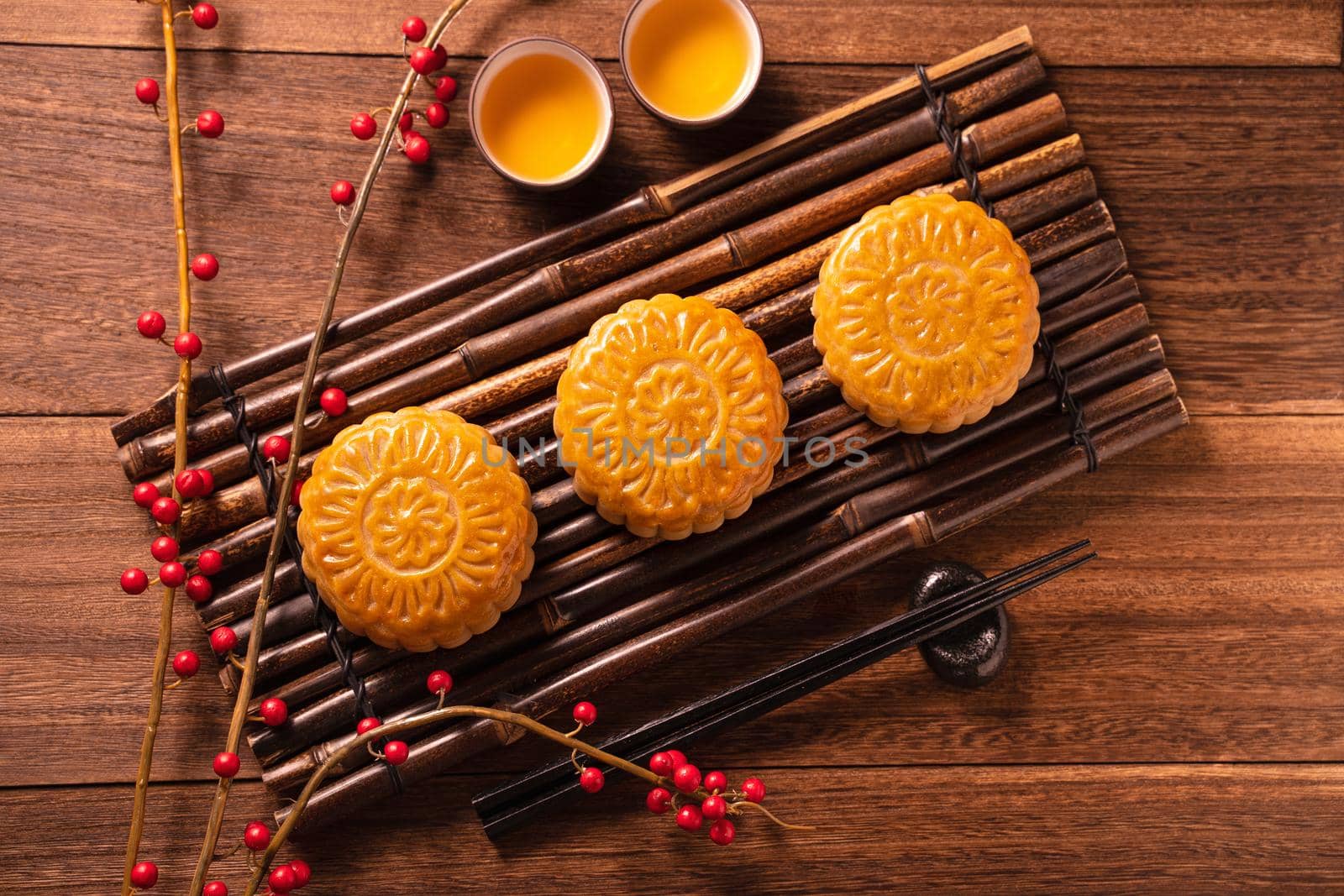 Chinese traditional pastry Moon cake Mooncake with tea cups on bamboo serving tray on wooden background for Mid-Autumn Festival, top view, flat lay.
