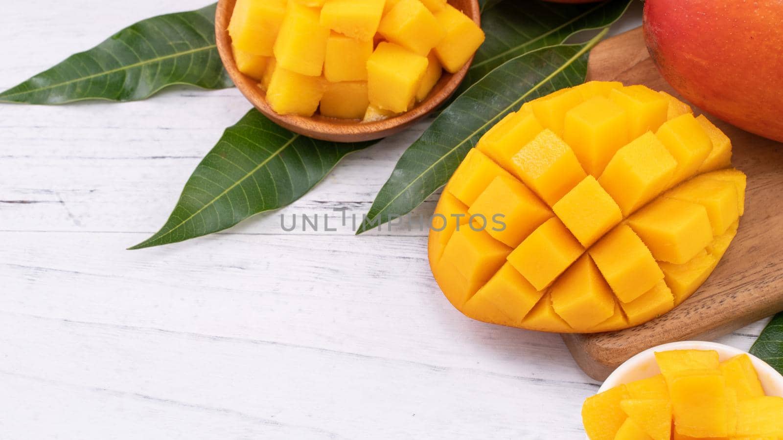 Fresh chopped mango on a tray and bright rustic wooden background. Tropical summer fruit design concept, close up, macro, copy space.