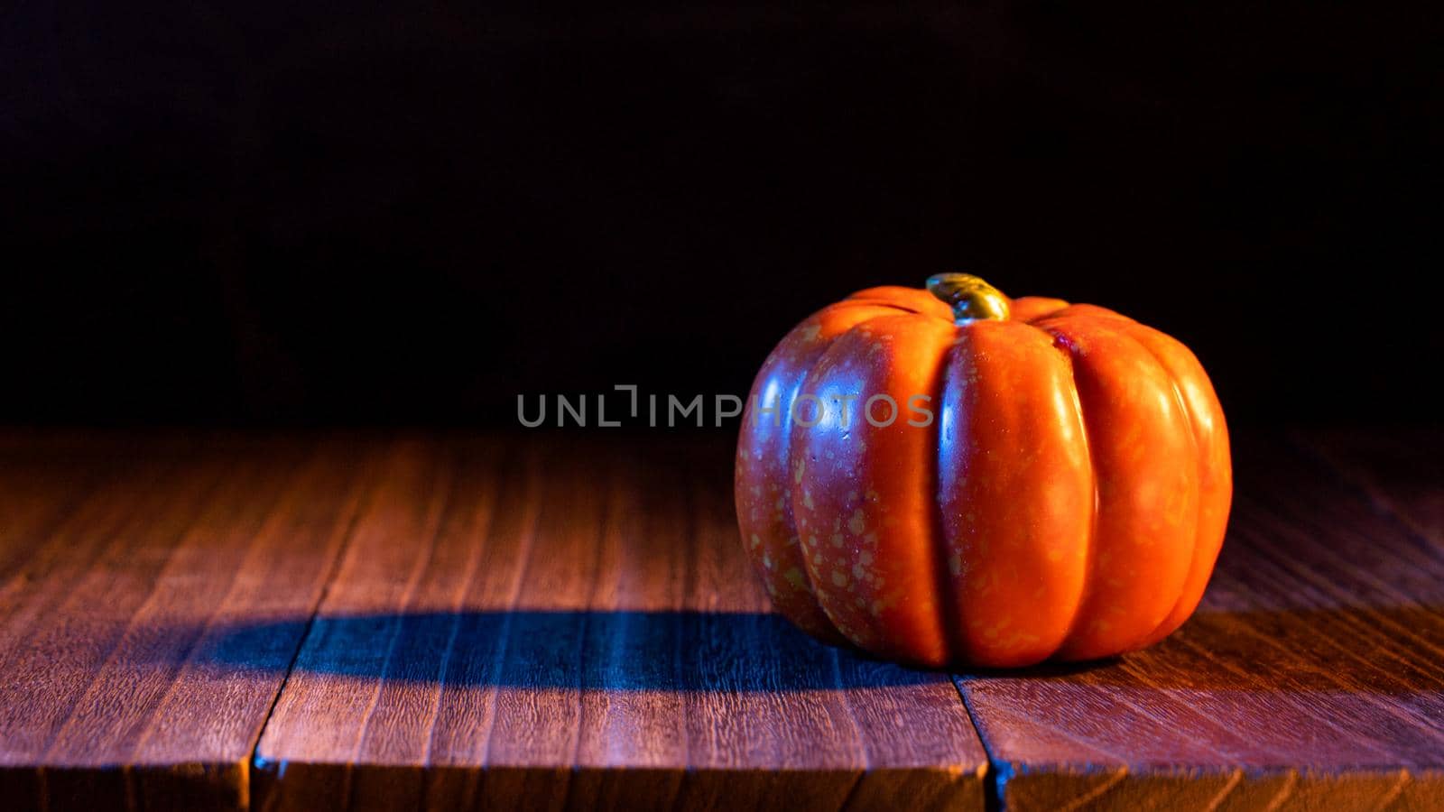 Halloween concept - Orange pumpkin lantern on a dark wooden table with black background, trick or treat, close up.