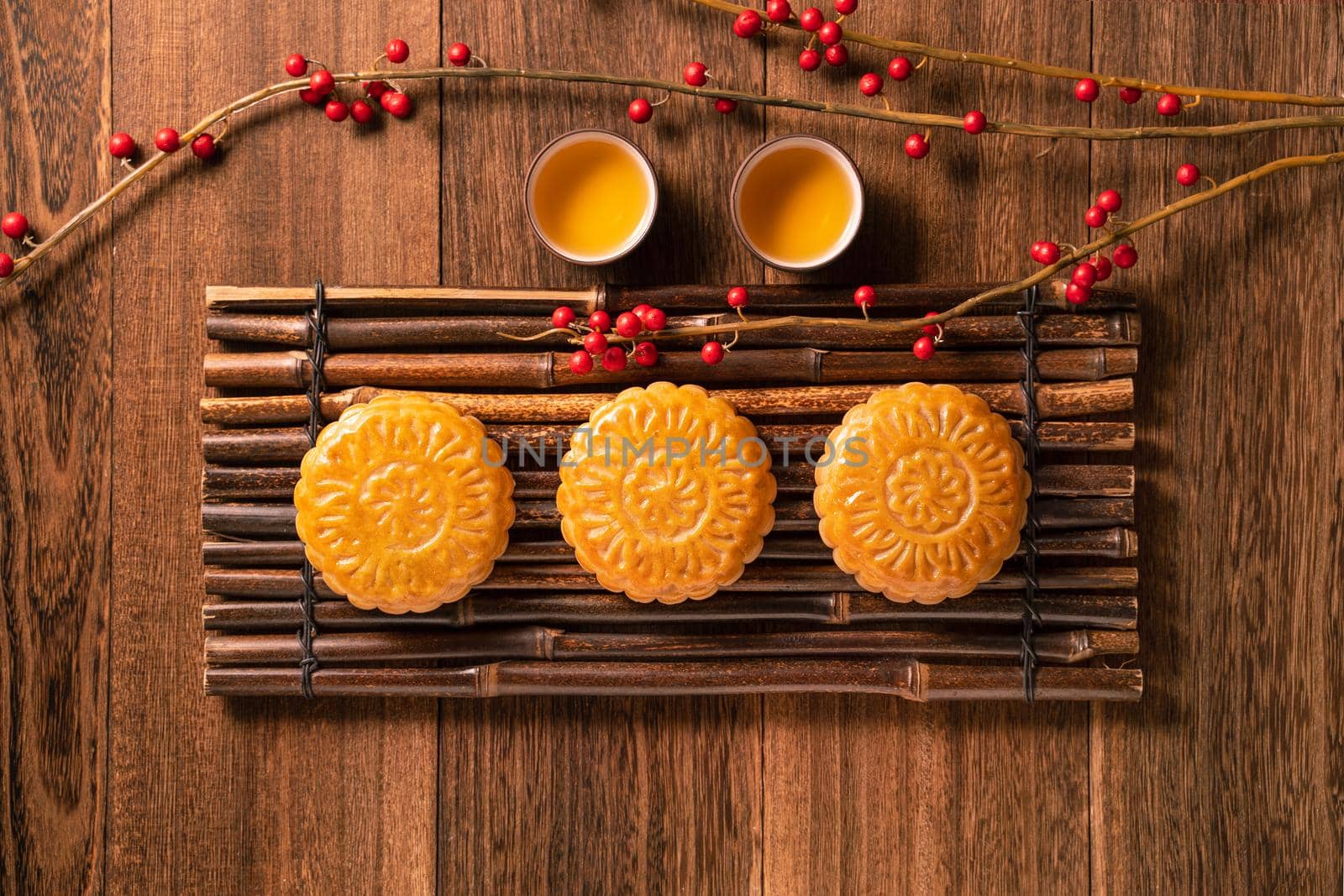 Chinese traditional pastry Moon cake Mooncake with tea cups on bamboo serving tray on wooden background for Mid-Autumn Festival, top view, flat lay.