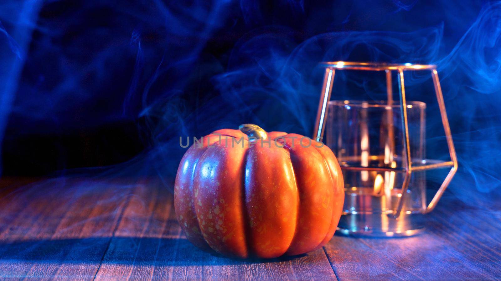 Halloween concept - Orange pumpkin lantern on a dark wooden table with double colored smoke around the background, trick or treat, close up.