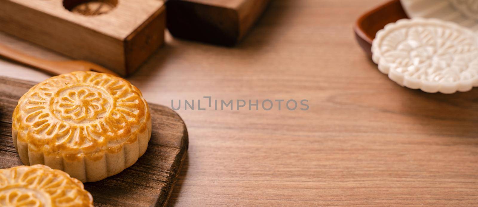 Round shaped fresh baked moon cake pastry - Chinese moonckae for Mid-Autumn Moon Festival on wooden background and serving tray, close up, copy space by ROMIXIMAGE