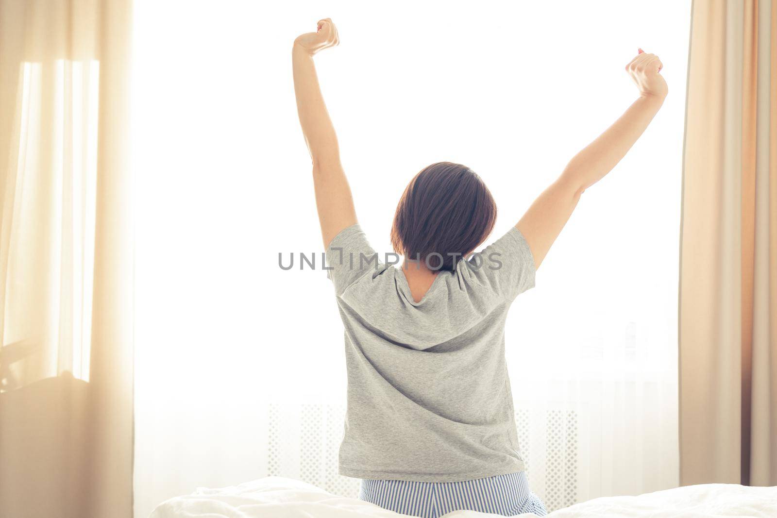 Woman stretching in bed room after good sleep by Mariakray
