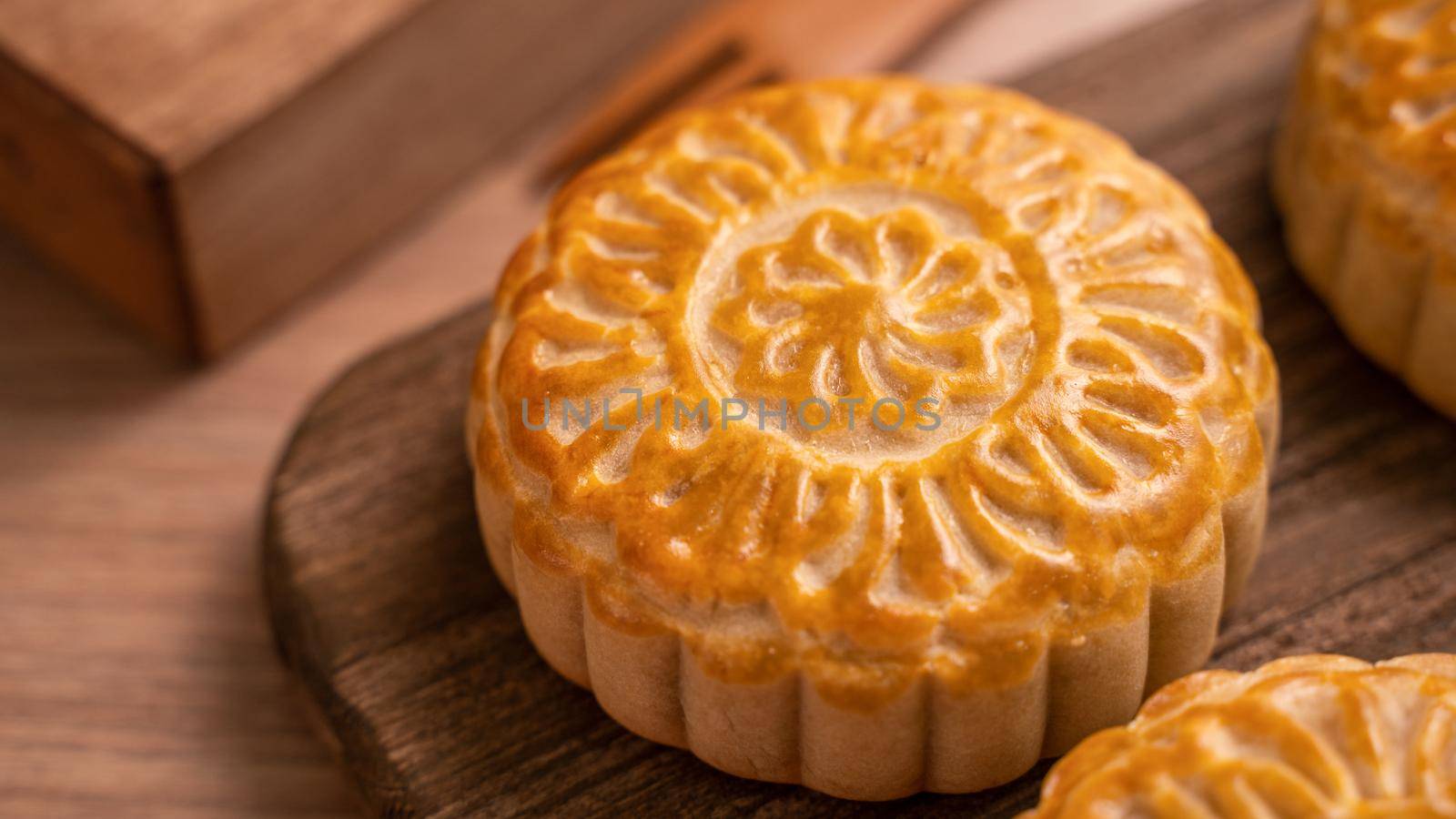 Round shaped fresh baked moon cake pastry - Chinese moonckae for Mid-Autumn Moon Festival on wooden background and serving tray, close up, copy space