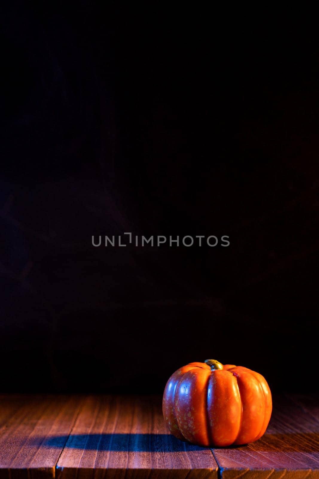 Halloween concept - Orange pumpkin lantern on a dark wooden table with black background, trick or treat, close up.