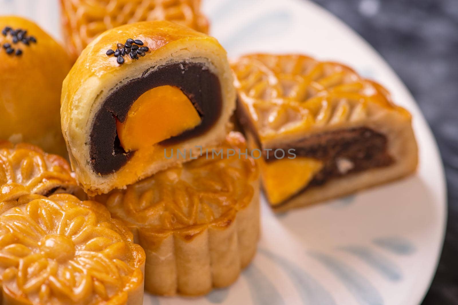 Tasty baked egg yolk pastry moon cake for Mid-Autumn Festival on black slate dark background. Chinese festive food concept, close up, copy space.