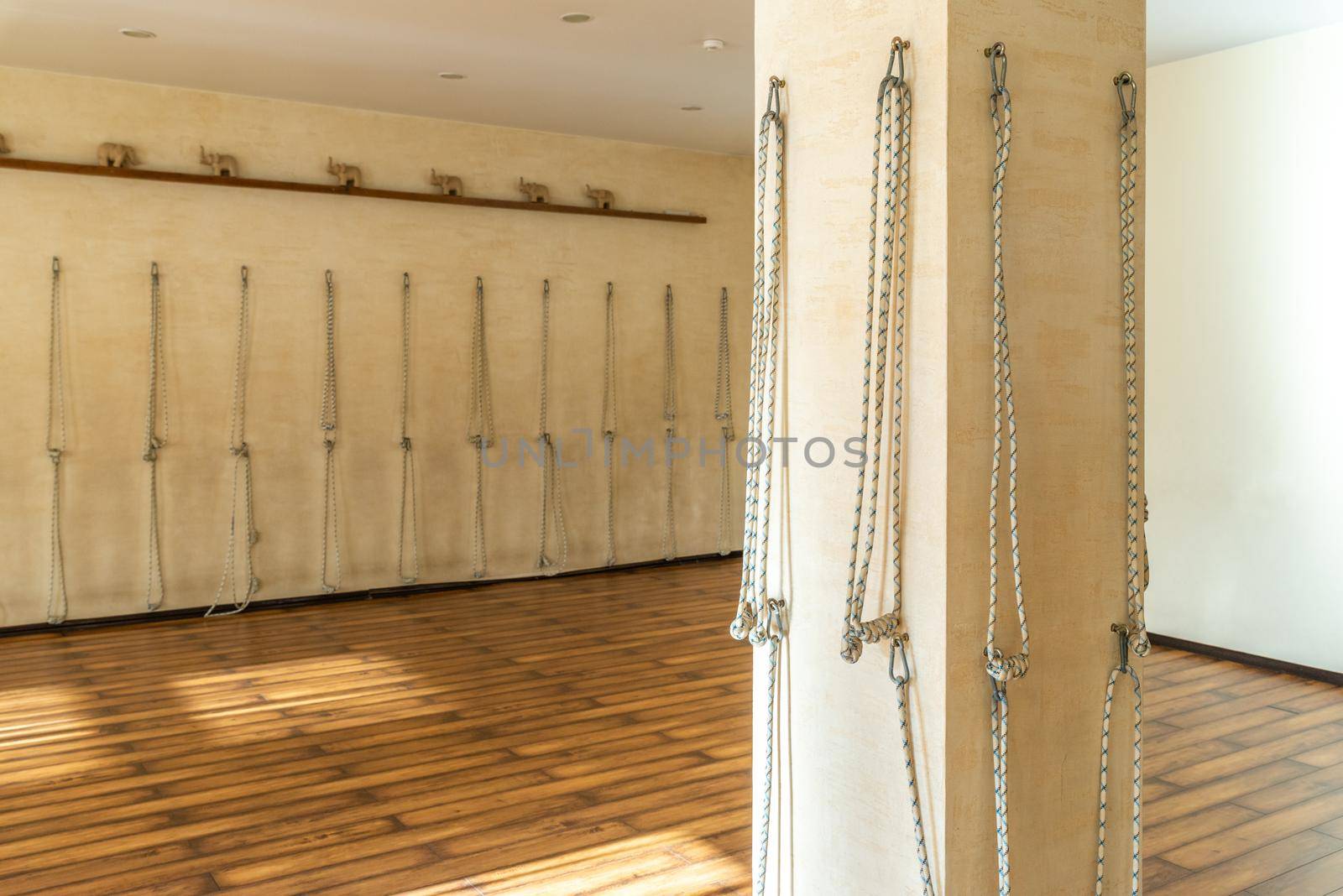 Yoga ropes hanging on studio wall. White background. Iyengar yoga props