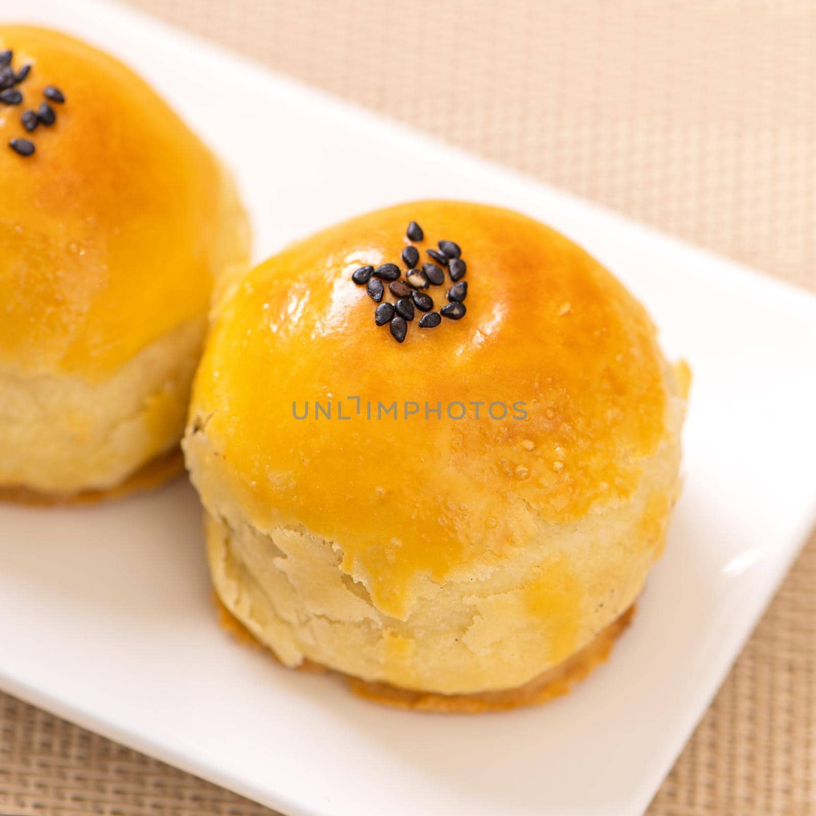 Tasty baked egg yolk pastry moon cake for Mid-Autumn Festival on bright wooden table background. Chinese festive food concept, close up, copy space.