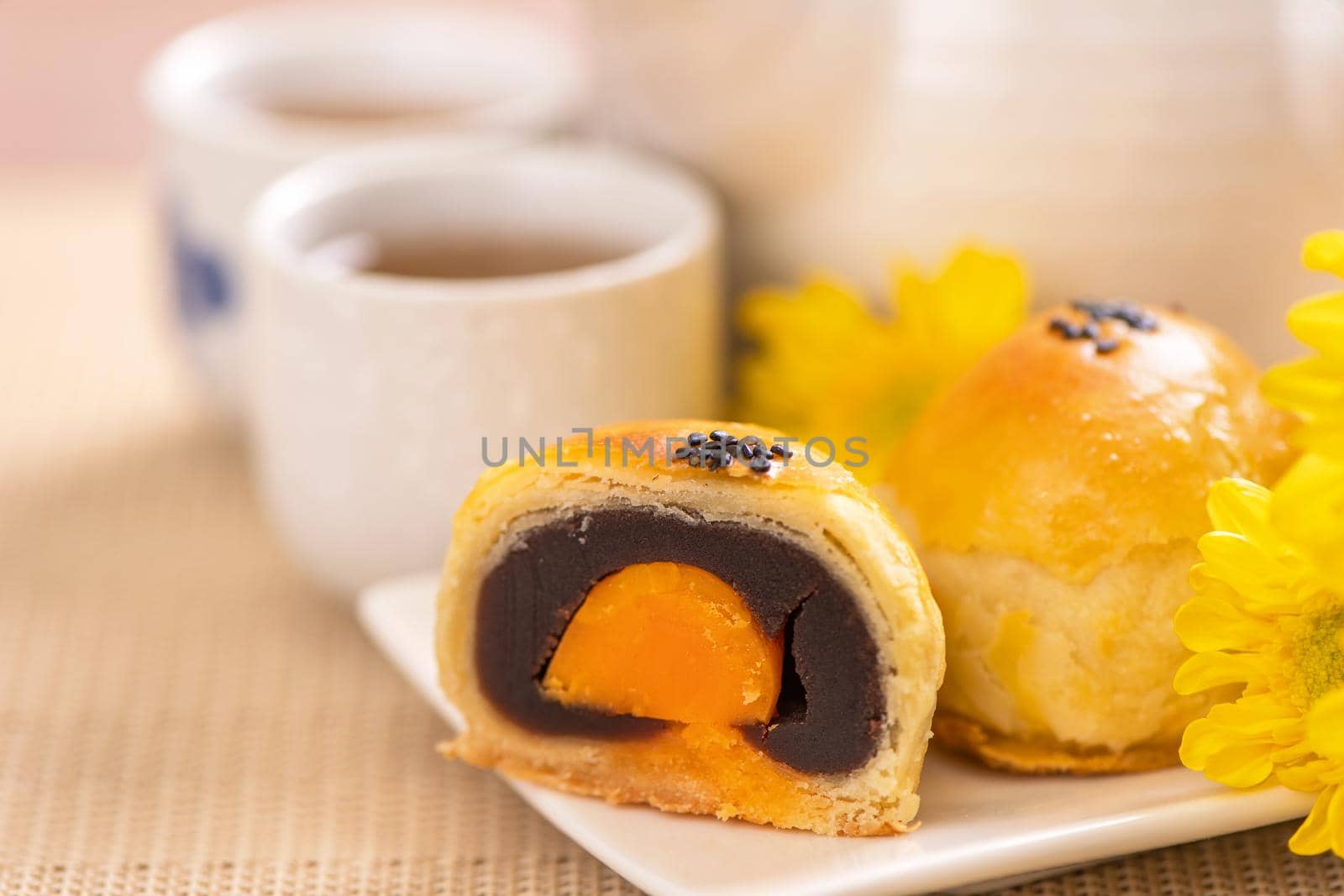 Tasty baked egg yolk pastry moon cake for Mid-Autumn Festival on bright wooden table background. Chinese festive food concept, close up, copy space.