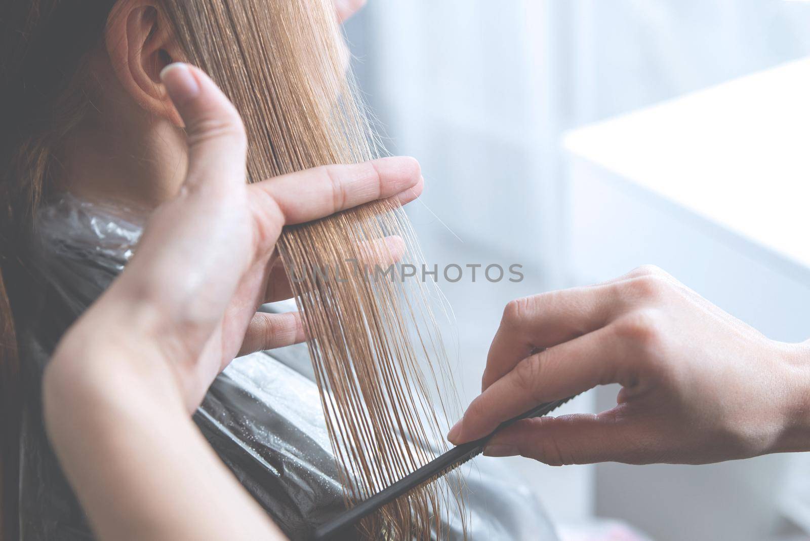 Hairdresser cut hair of a blonde young woman in hair salon, haze effect by Mariakray