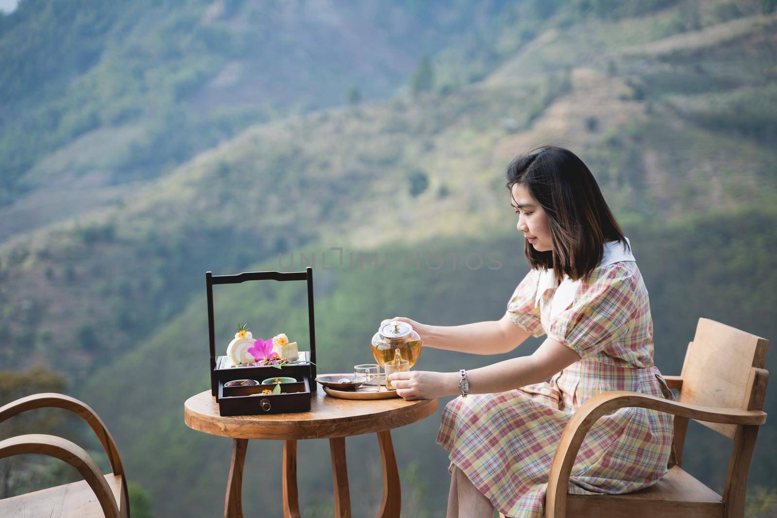 beautiful women drinking hot green tea sitting on the chair mountain view by Wmpix