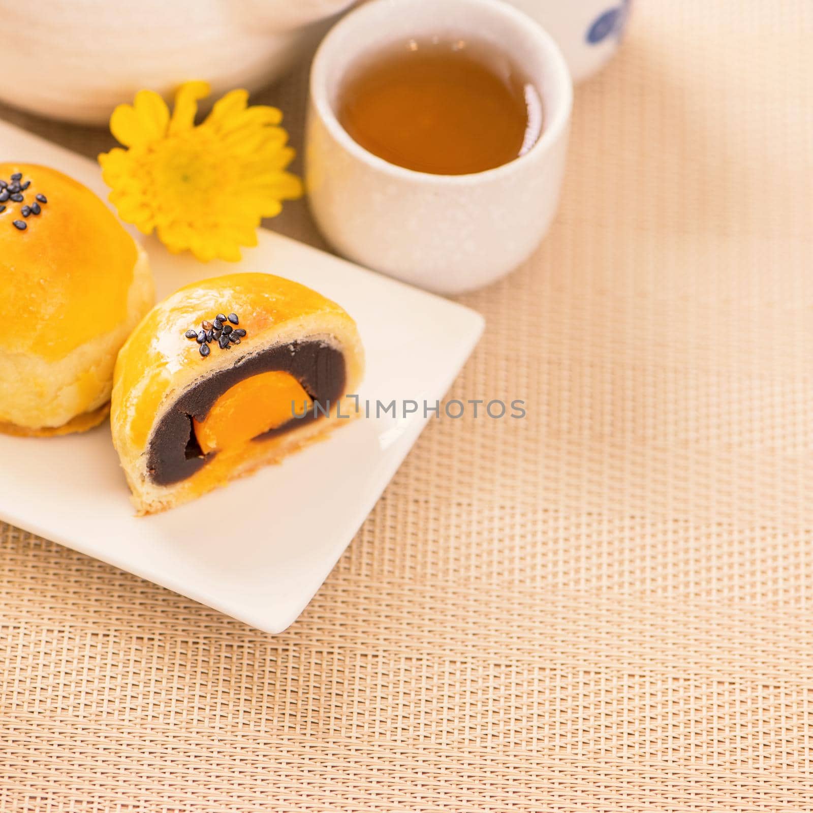 Tasty baked egg yolk pastry moon cake for Mid-Autumn Festival on bright wooden table background. Chinese festive food concept, close up, copy space.