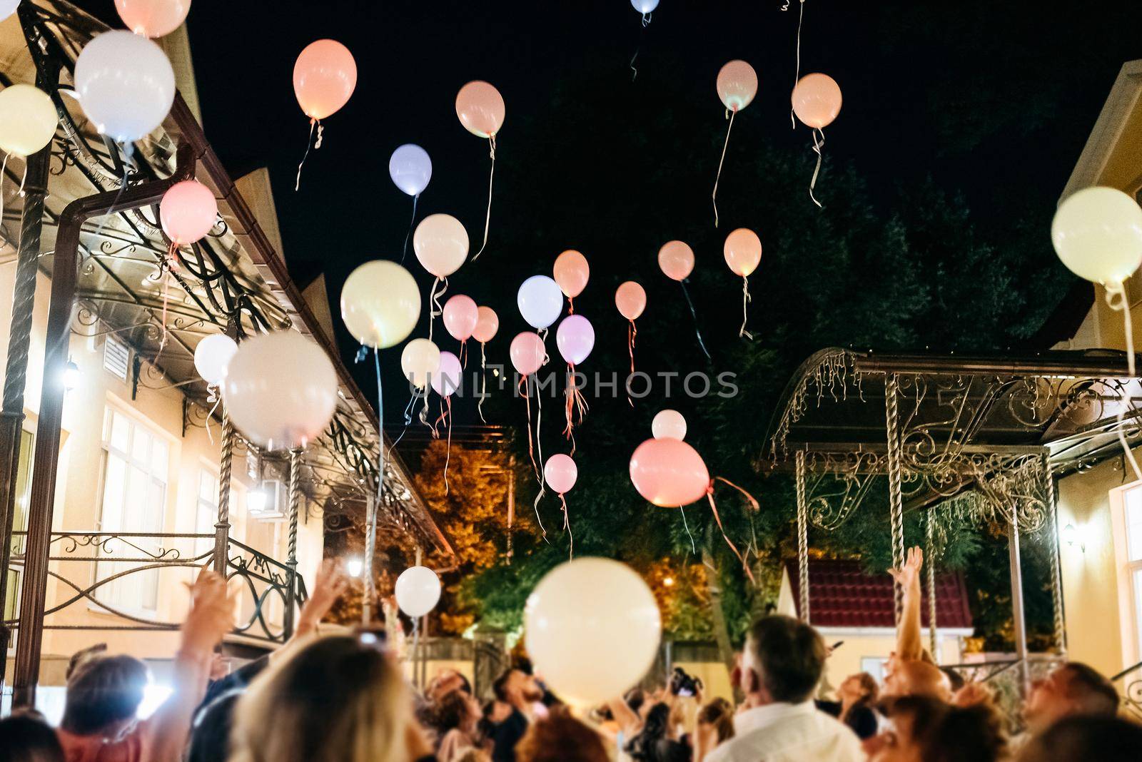 Crowd Throwing Colorful Balloons to Sky at night During Festival or wedding party by Mariakray