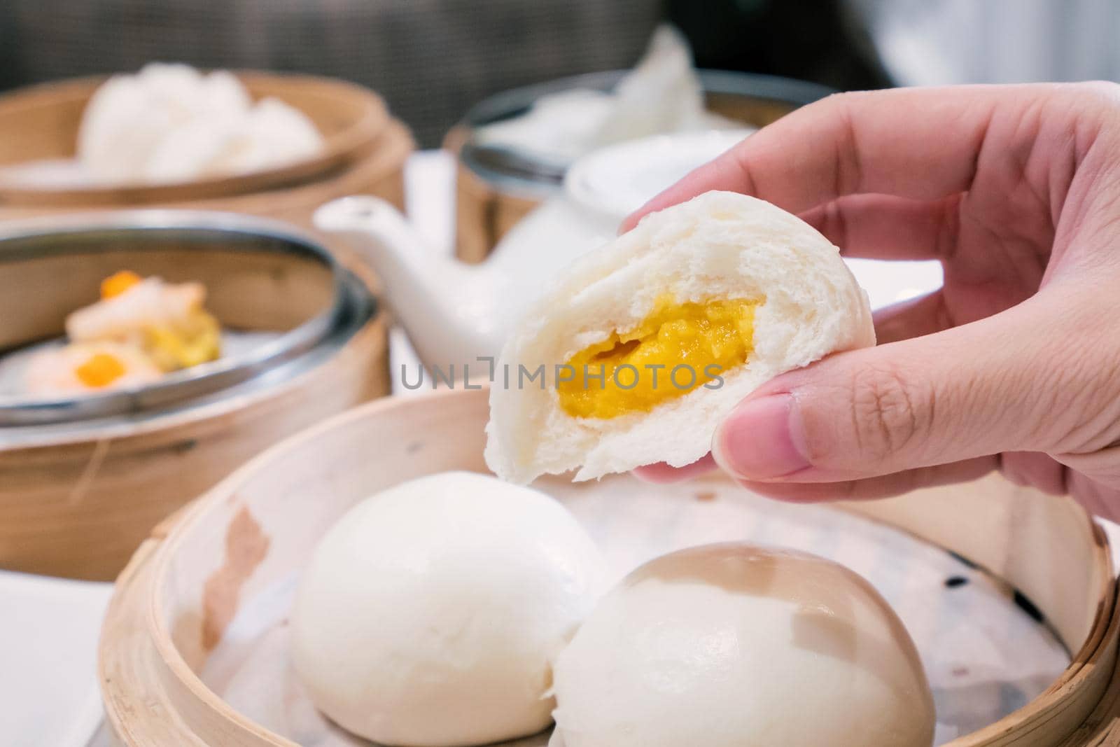 Delicious dim sum, famous cantonese food in asia, fresh and hot salted creamy custard buns in bamboo steamer in hong kong yumcha restaurant, close up