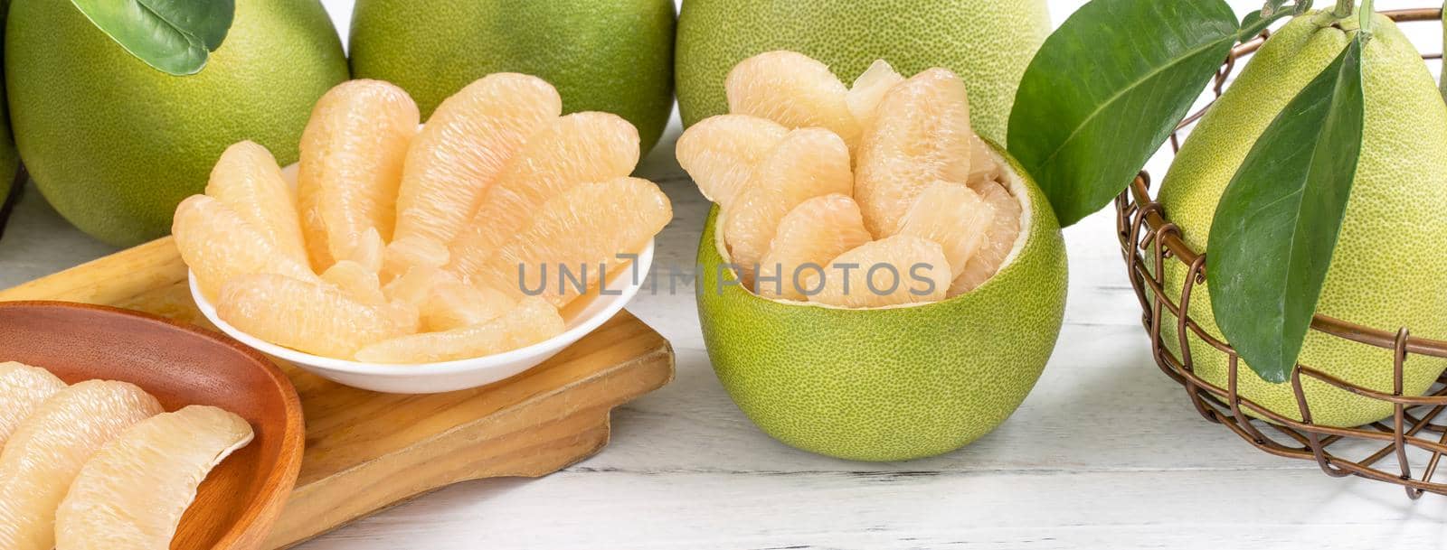 Fresh peeled pomelo, grapefruit, shaddock with green leaf on bright wooden plank table. Seasonal fruit near mid-autumn festival, close up, copy space
