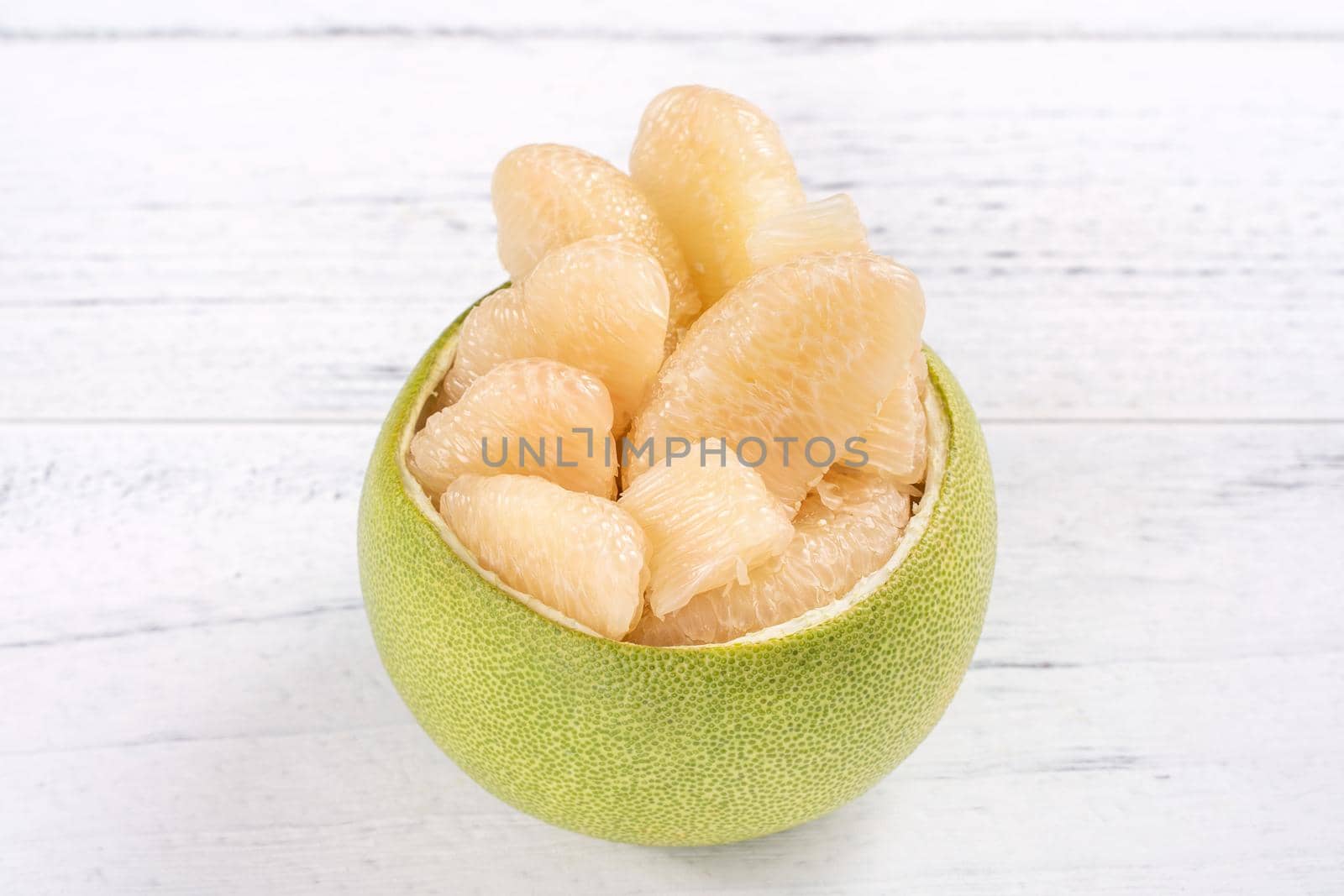 Fresh peeled pomelo, grapefruit, shaddock with green leaf on bright wooden plank table. Seasonal fruit near mid-autumn festival, close up, copy space
