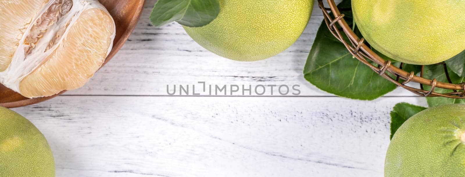 Fresh peeled pomelo, grapefruit, shaddock with green leaf on bright wooden plank table. Seasonal fruit near mid-autumn festival, top view, copy space by ROMIXIMAGE